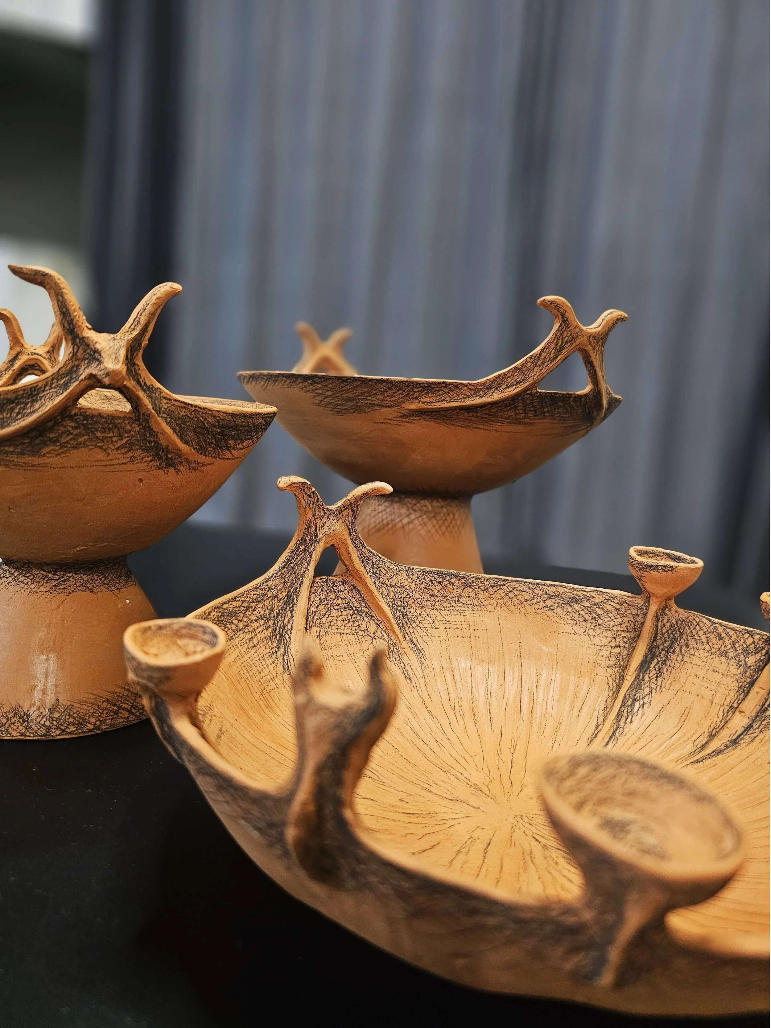 Three hand-built terracotta vessels inspired by ancient Greek pottery, decorated with black underglaze pencil
