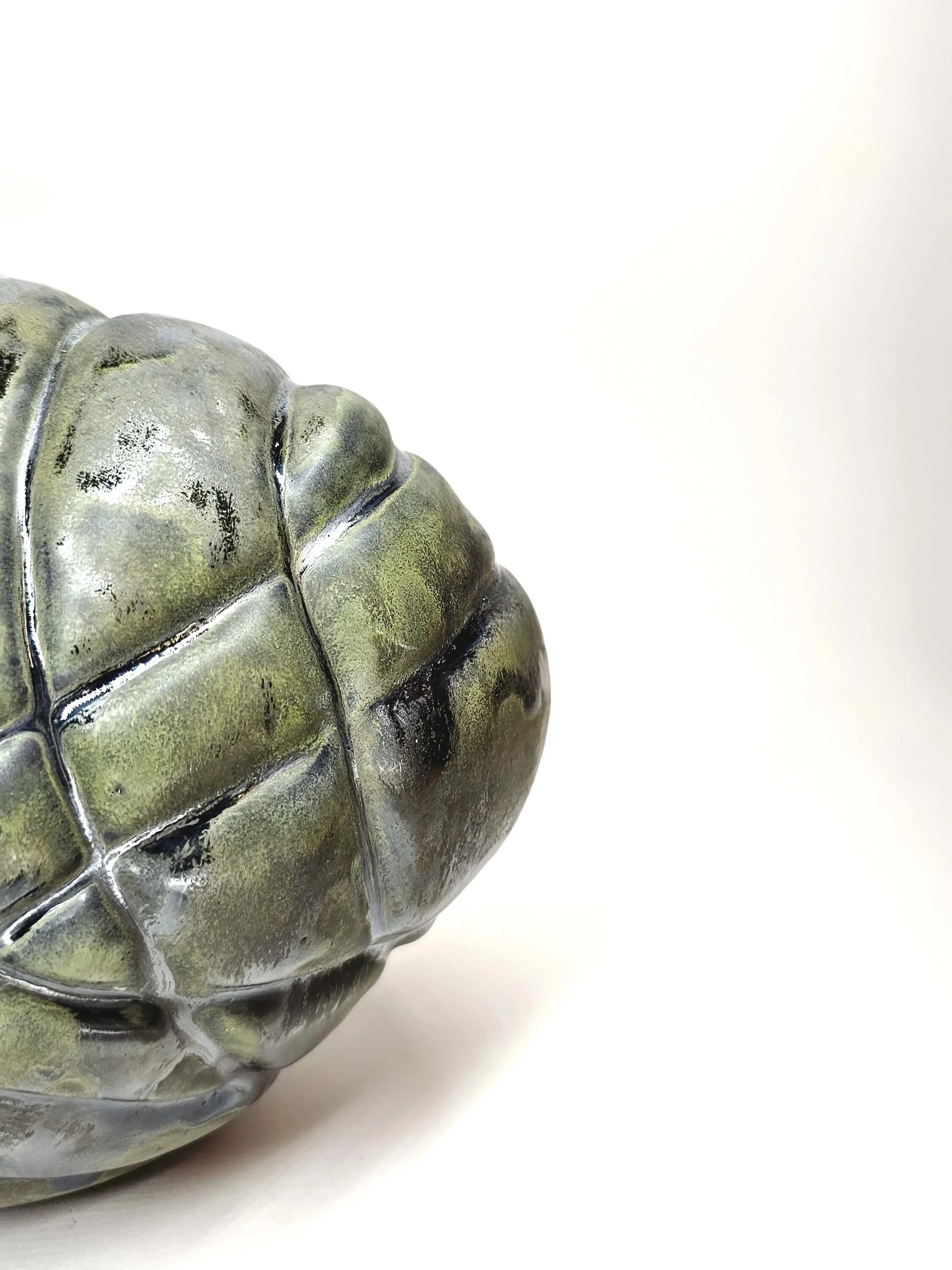 Mirsini Roumelioti. Mirsini Ceramics. Asphyxia. Hugs. Close-up of a metallic turtle sculpture, showing the detailed shell with greenish-black and silver tones, against a white background.