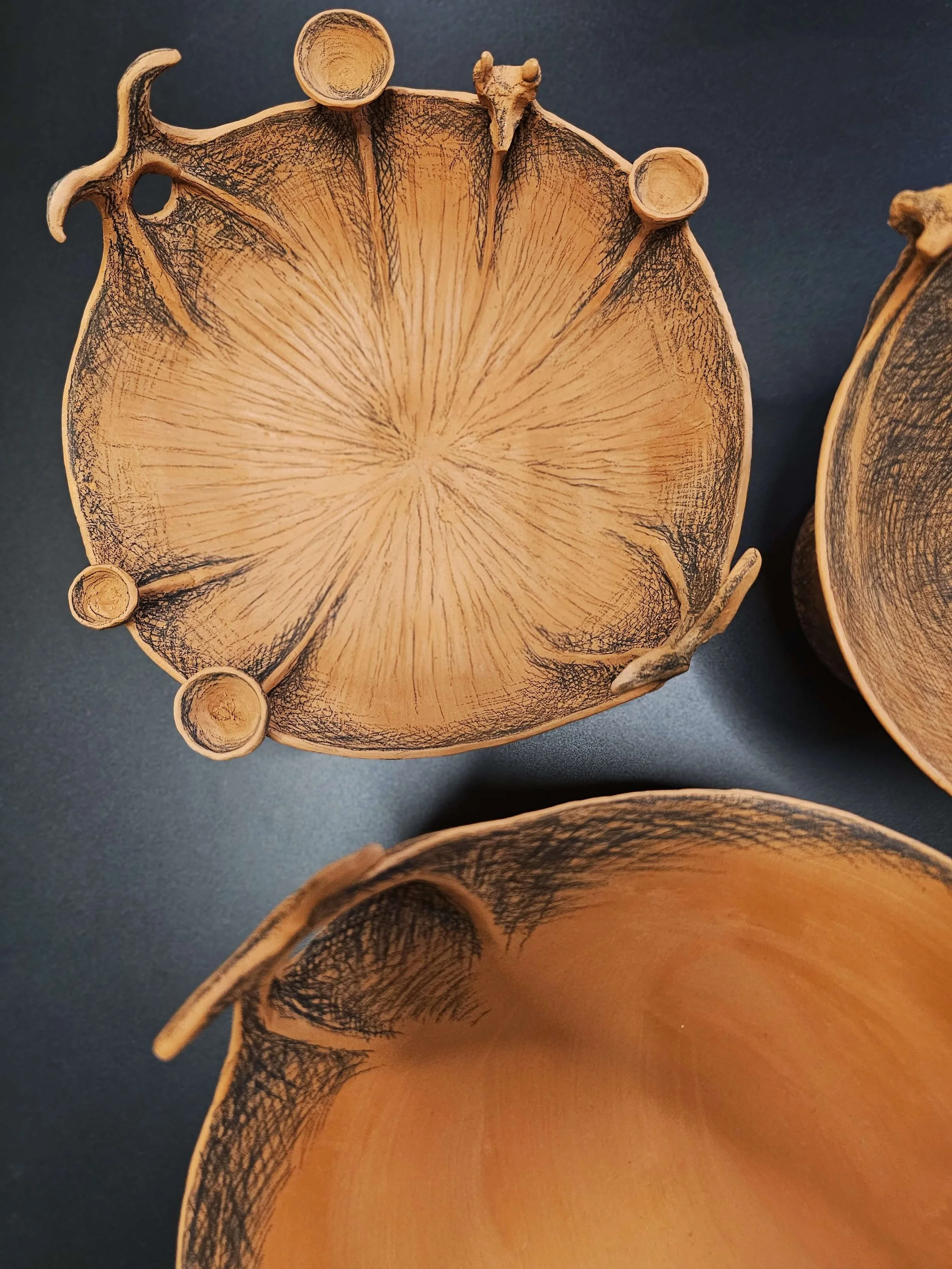 Three hand-built terracotta vessels inspired by ancient Greek pottery, decorated with black underglaze pencil