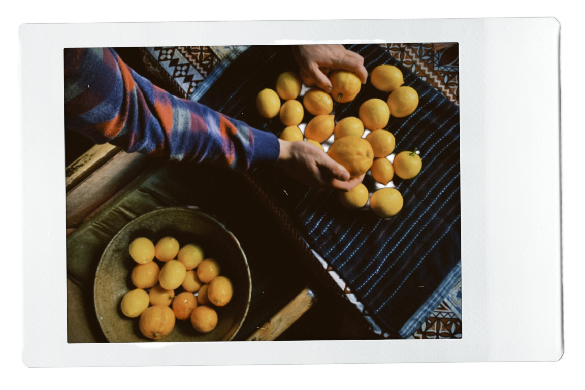Person sorting lemons on a dark cloth, with a bowl of more lemons nearby.