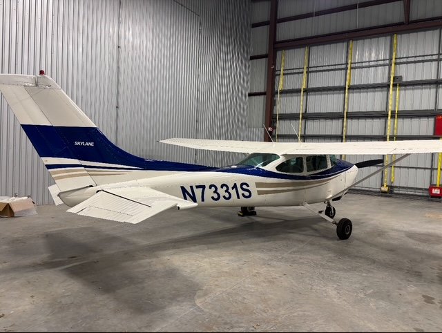Small white and blue single-engine airplane inside a hangar.