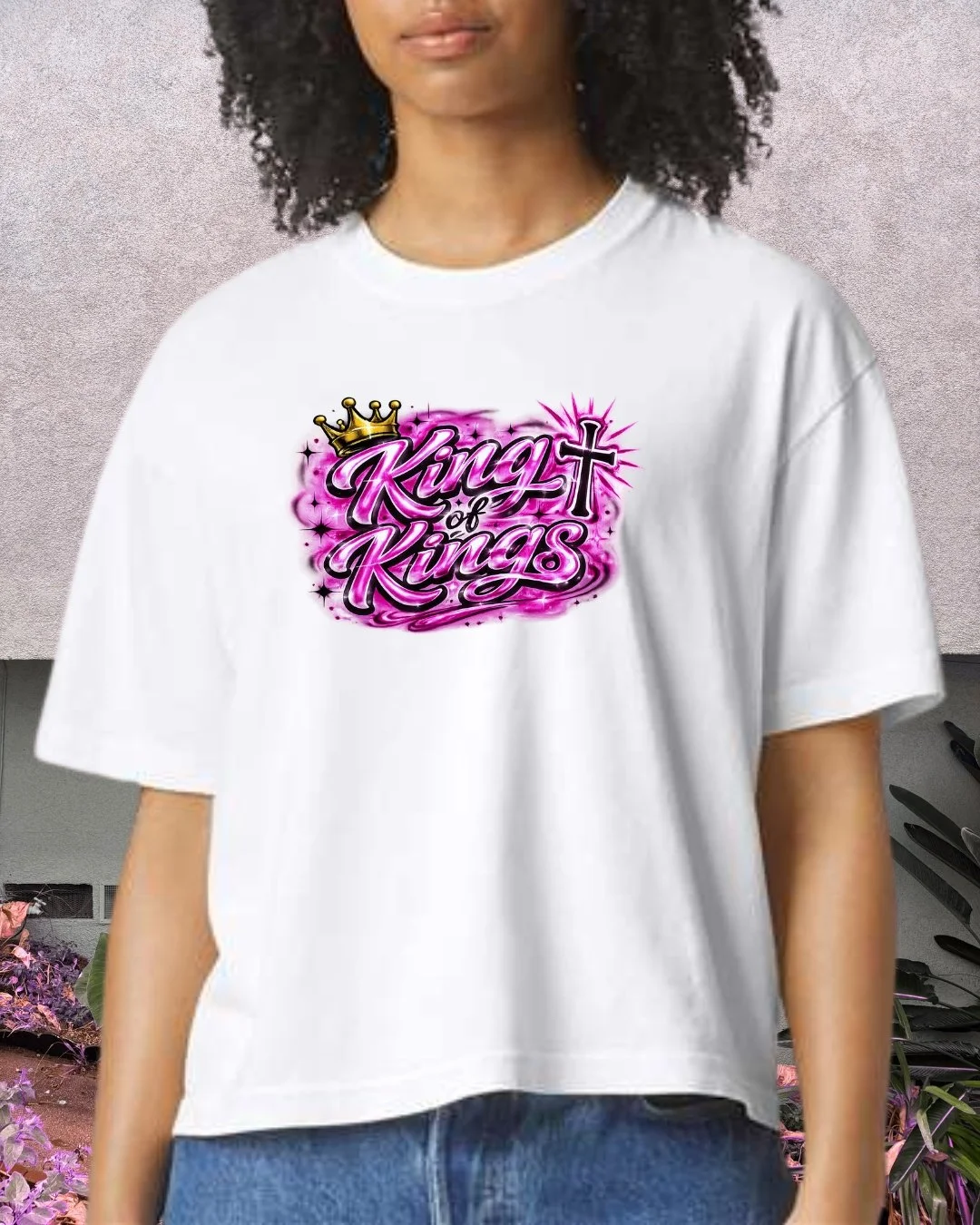 Model wearing KingsHope King of Kings white crop tee with pink airbrush crown and cross graphic