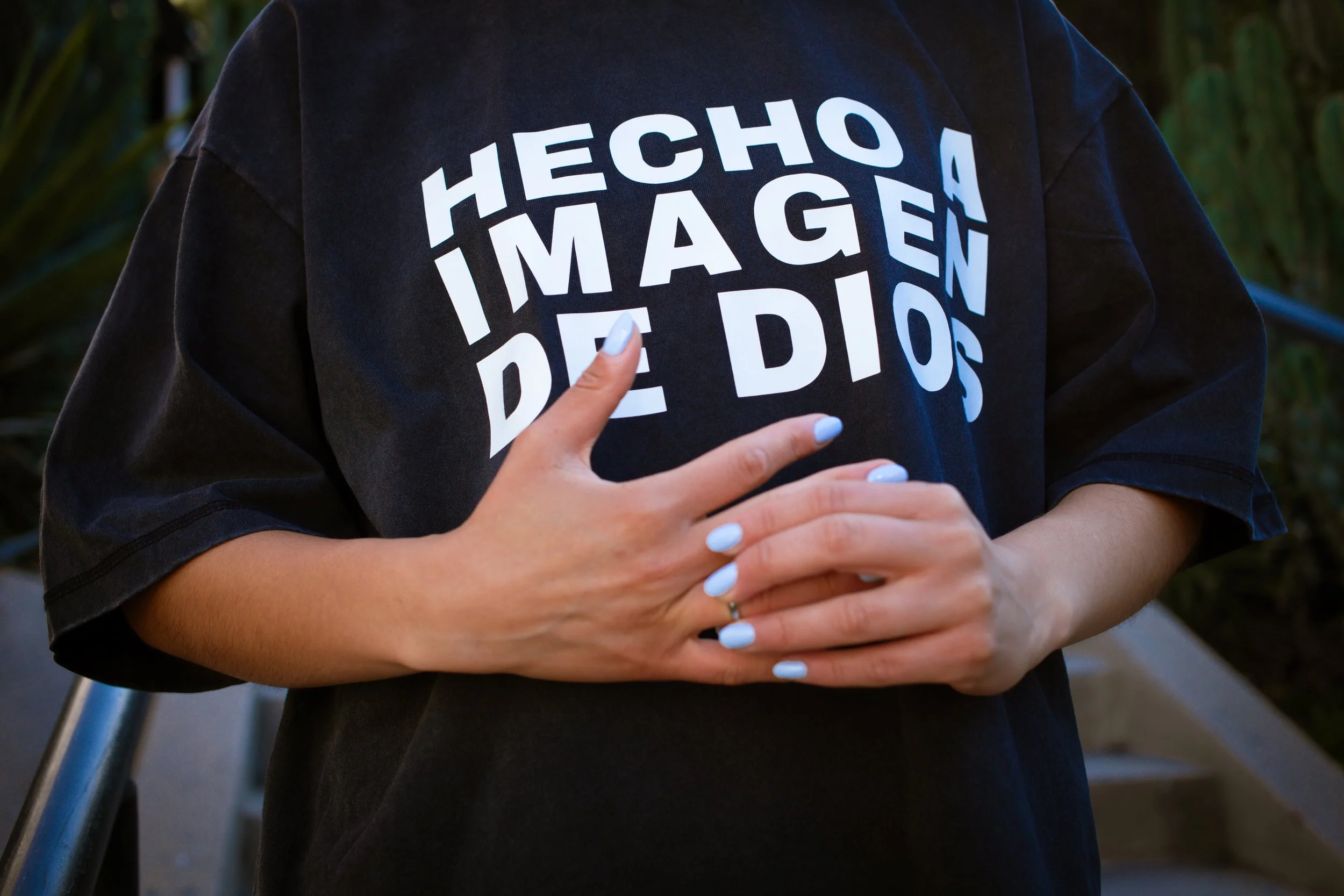 Close-up of Hecho A Imagen De Dios bold white print on charcoal crop tee