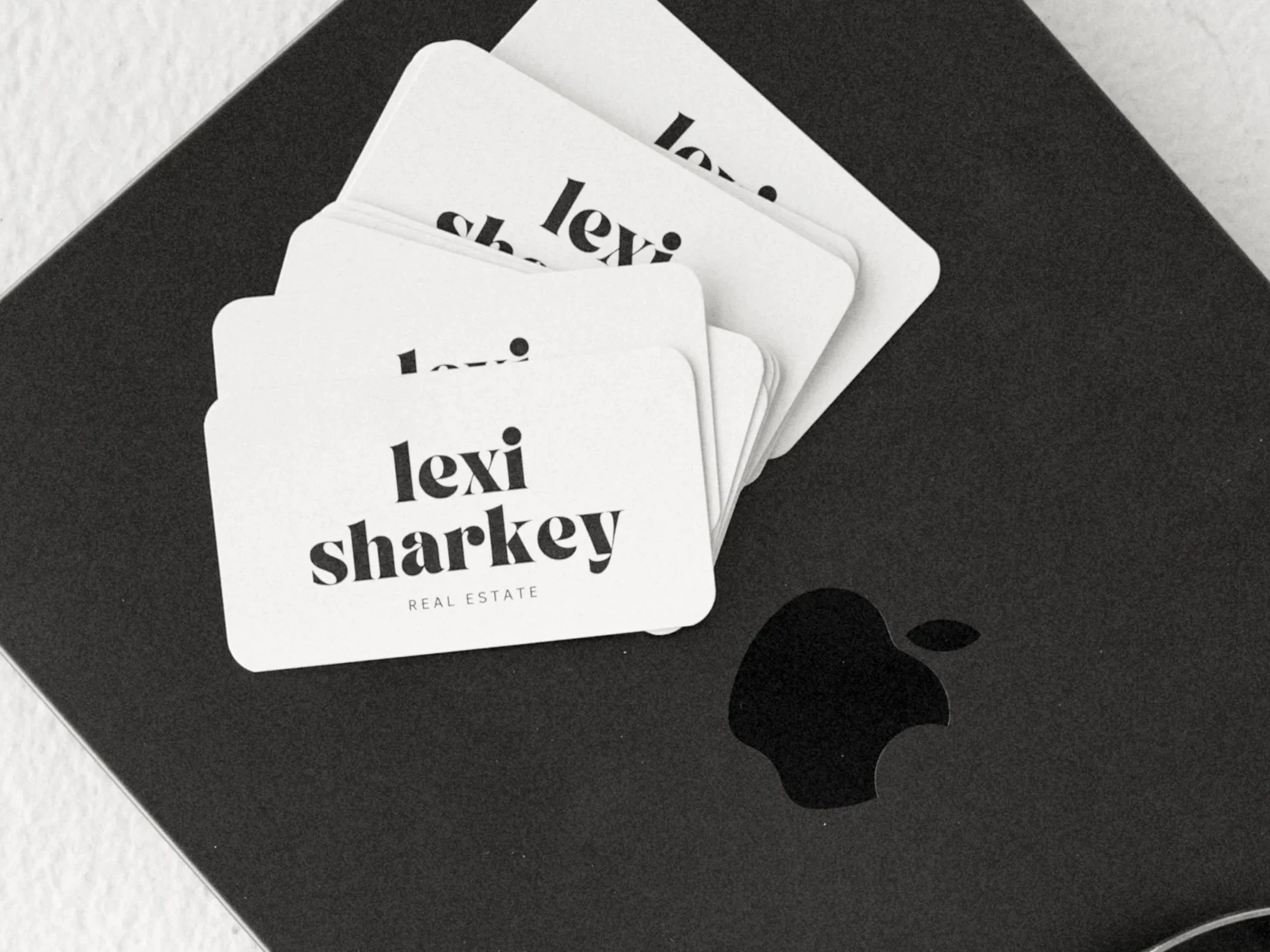 Black box with white cards displaying the name 'Lexi Sharkey' and the words 'Real Estate' underneath.