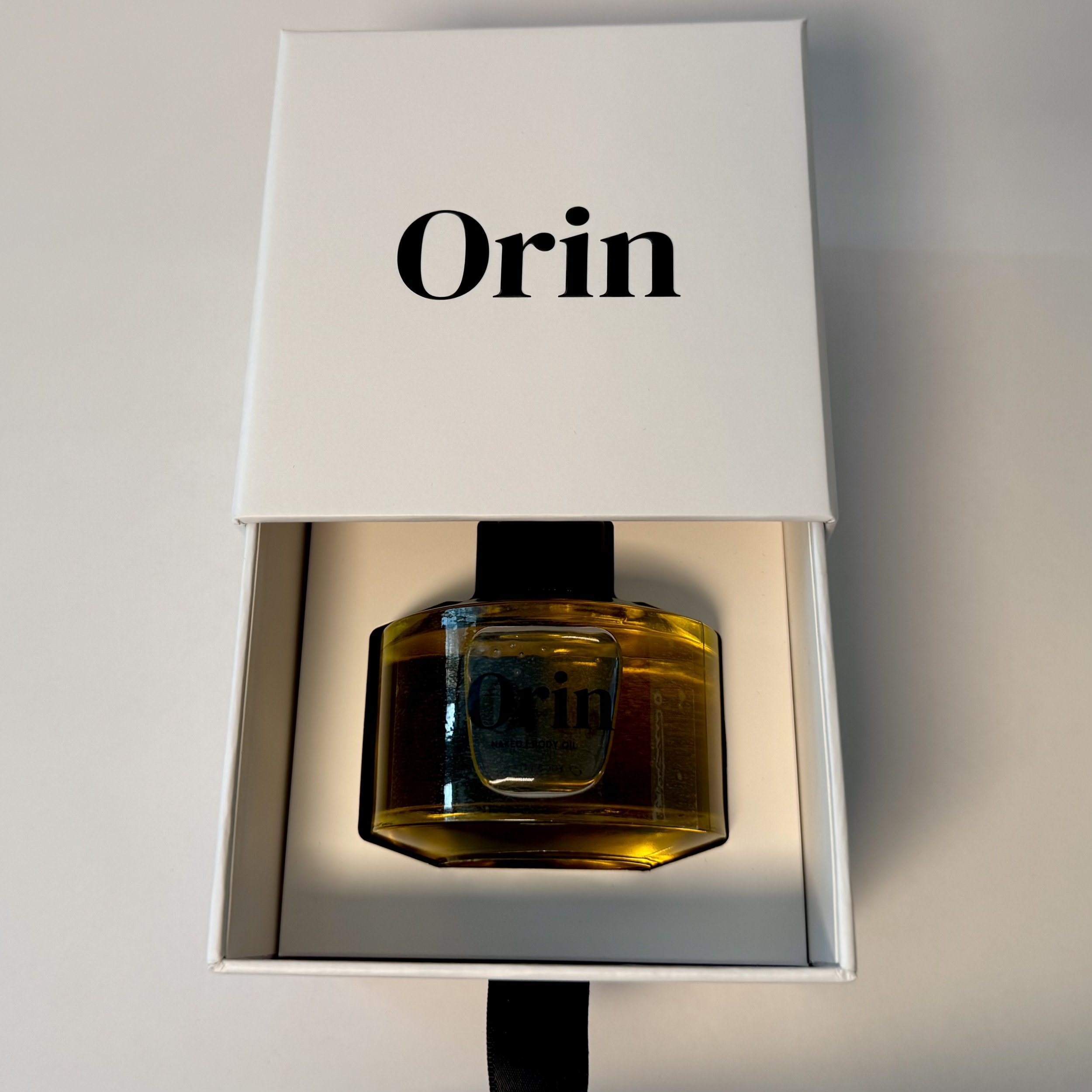 100ml Orin Naked Body Oil securely nestled in an open white luxury drawer box. This premium presentation showcases the fragrance-free botanical oil, formulated for pure, receptive nourishment.