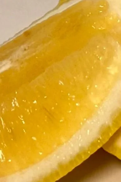 A close-up of fresh yuzu fruits with water droplets, illustrating the brightening, energizing botanical properties of the Orin Yuzu Botanical Body Oil.