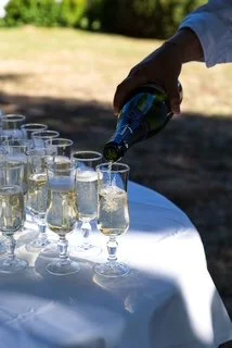 Person pouring champagne into glasses on a table outside