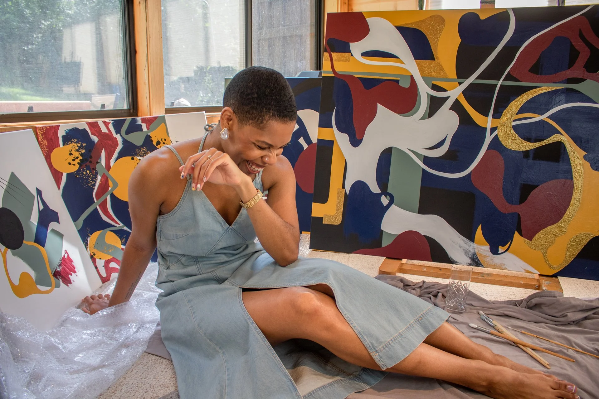 Portrait of Minnesota abstract artist Nailah Ali smiling among original abstract paintings from the Moments in Grief collection.