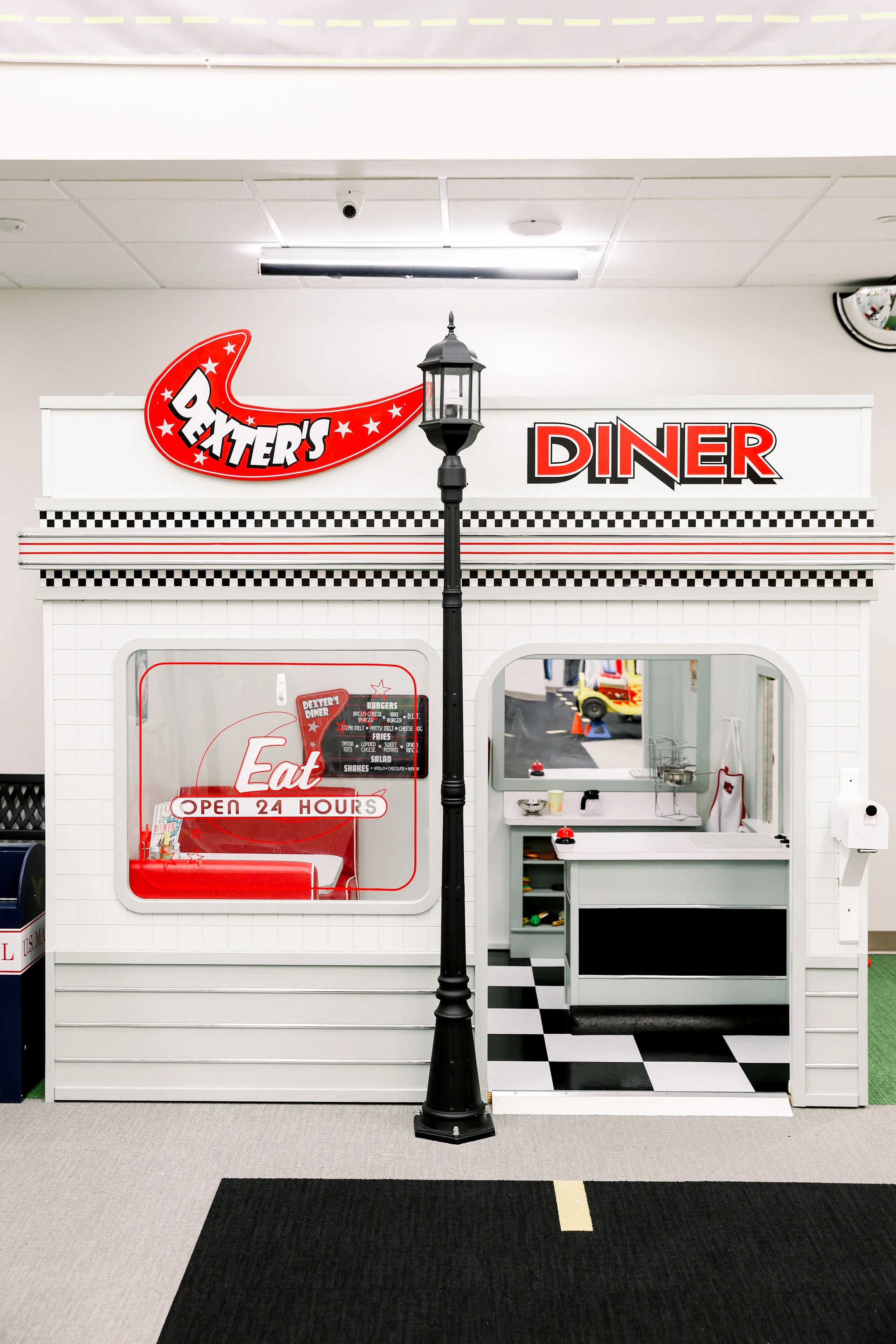 Miniature vintage-style diner with a sign that says 'Dart's Diner', a window displaying an 'Eat' sign, and a small serving counter with checkered flooring.