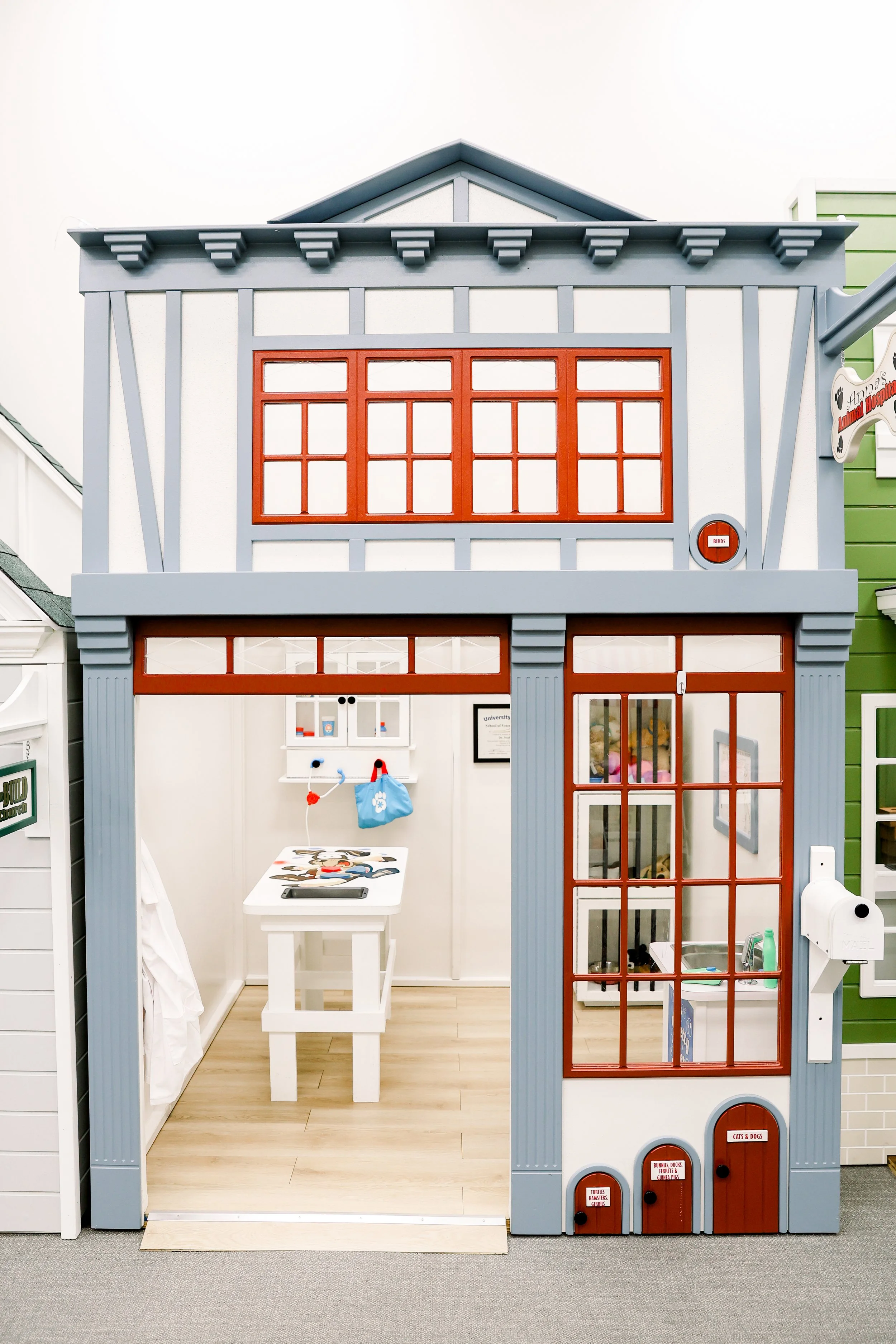 A miniature model of a two-story storefront with large windows and door made of wood and glass, featuring a mailbox outside.