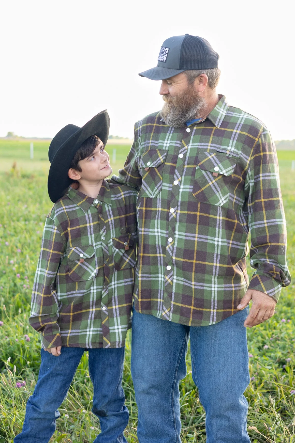 Dad and son smiling at each other in a country farmland setting in North Manchester