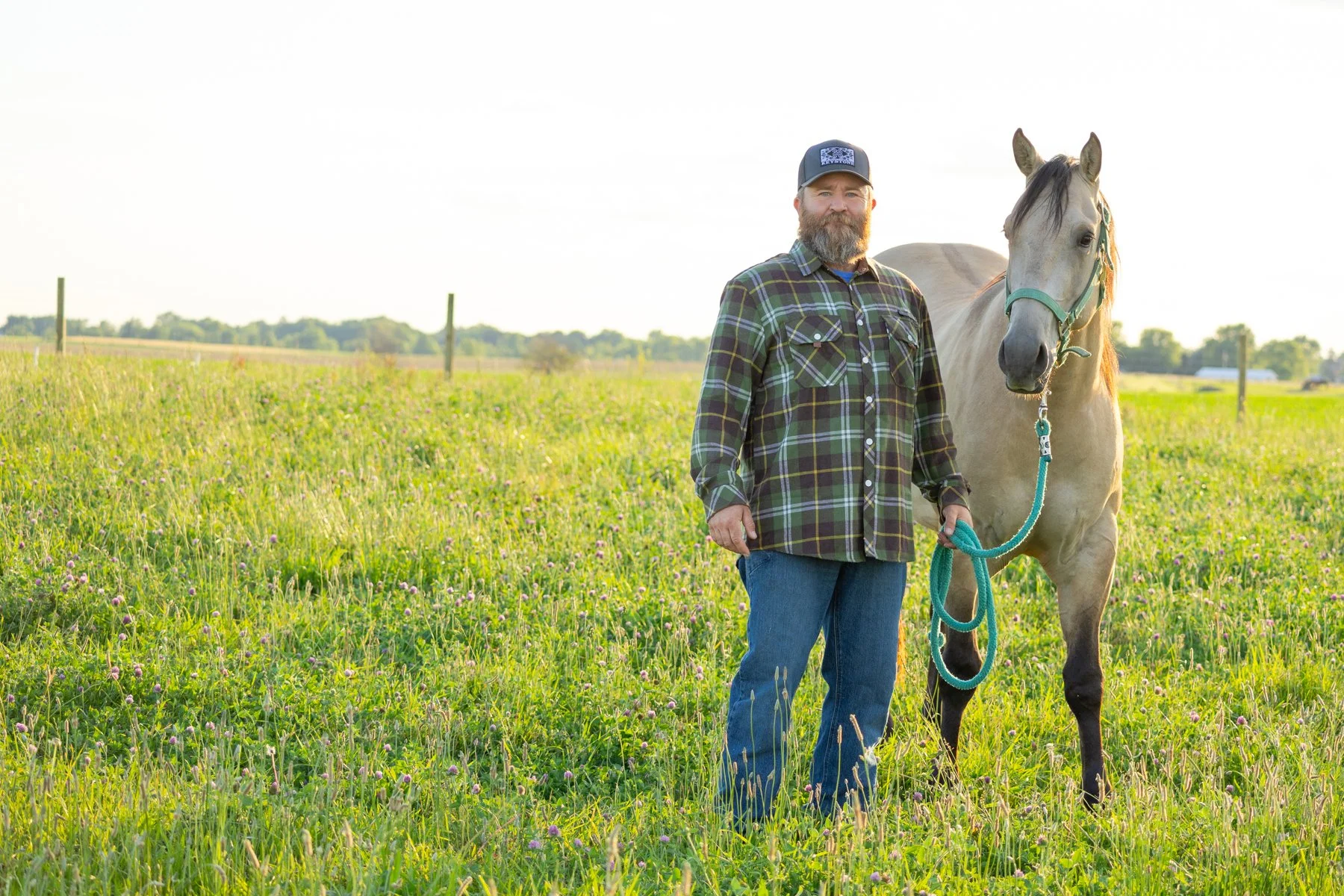 Man and horse together in a grassy farm field setting photographed in North Manchester, Indiana at sunset time