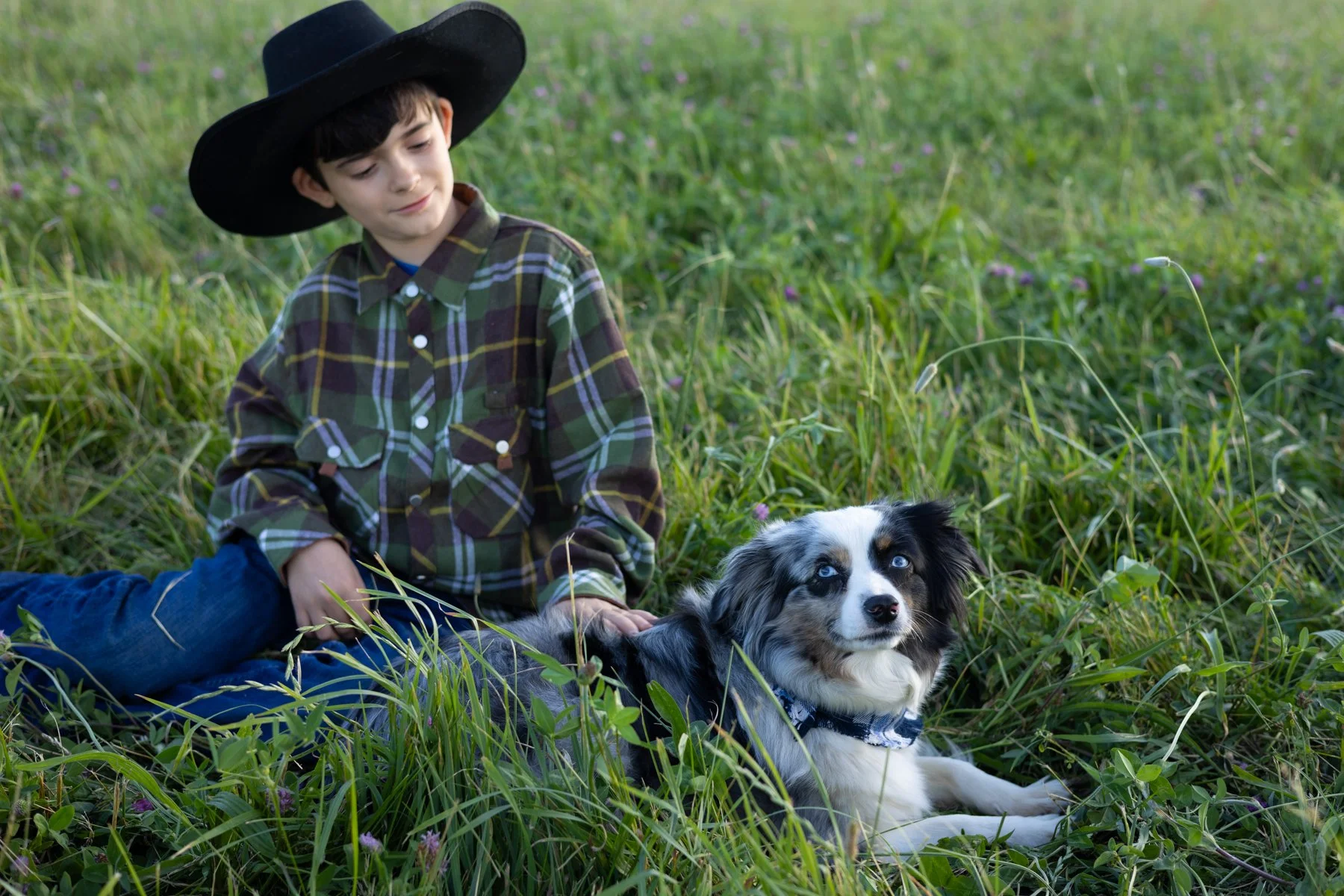 Boy and dog sitting together in tall grasses in a farm field in Indiana