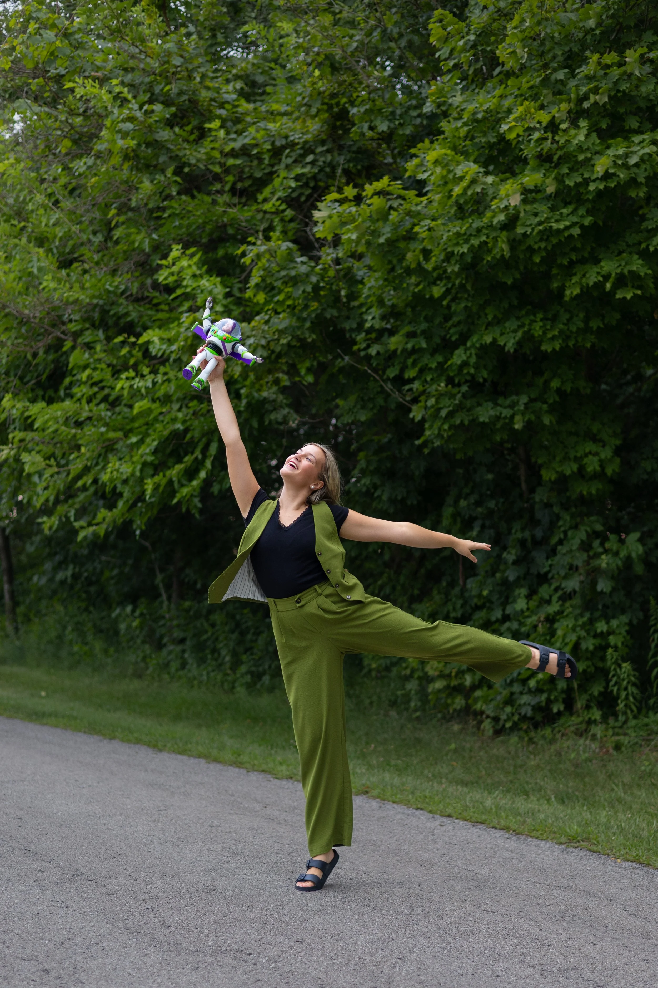 senior is dancing with toy in a meaningful candid photograph taken in Huntington with trees behind and natural vibes
