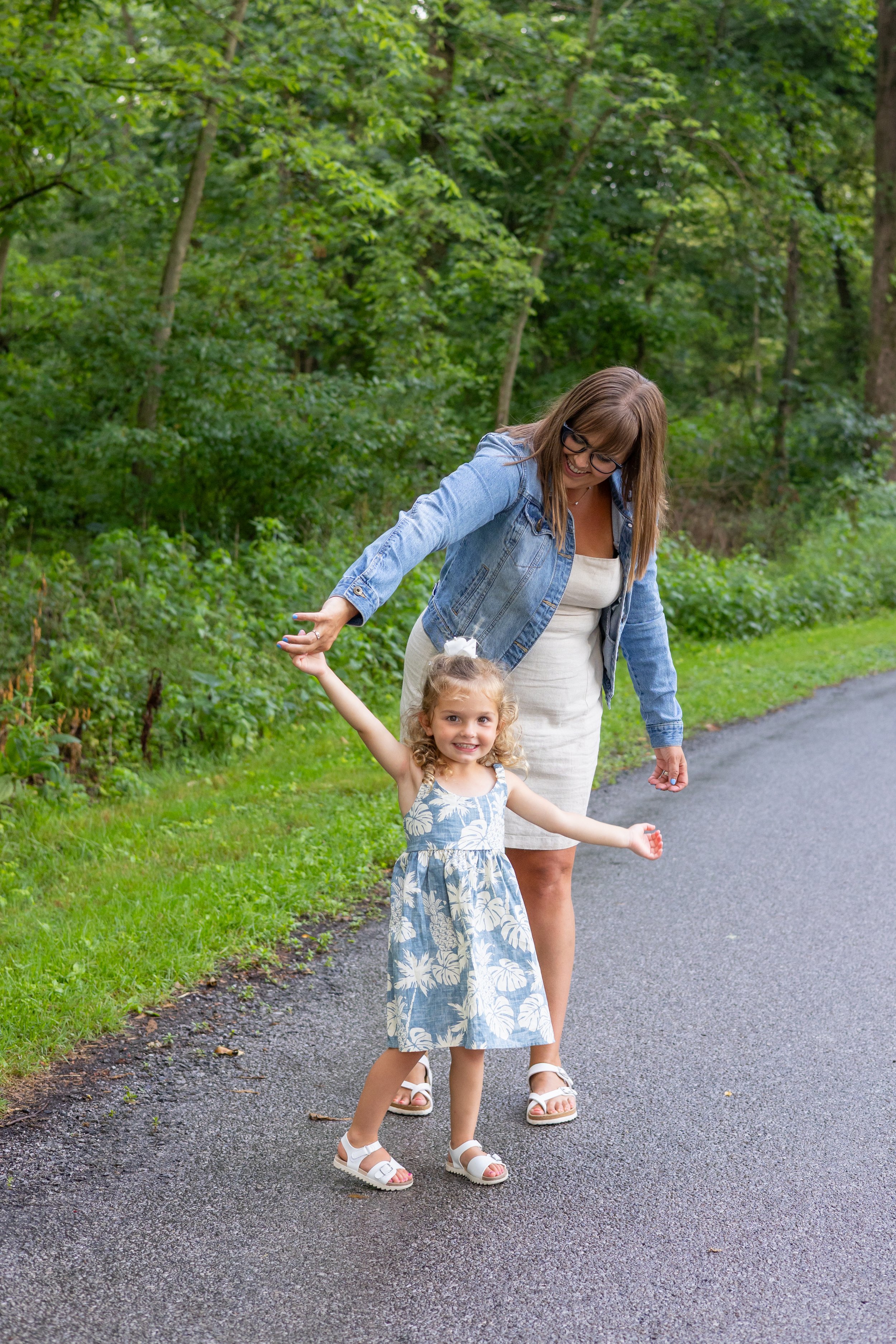 Mom and daughter twirling in Huntington Indiana with trees behind them just after a rain