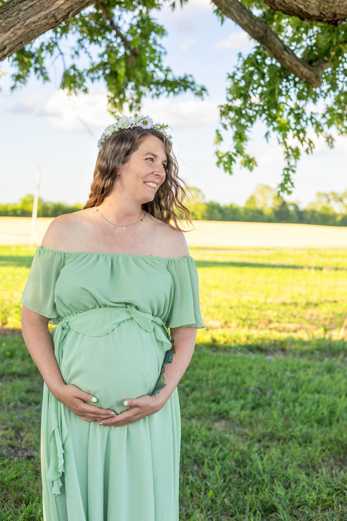 Expectant mother standing under a tree in farmland in North Manchester