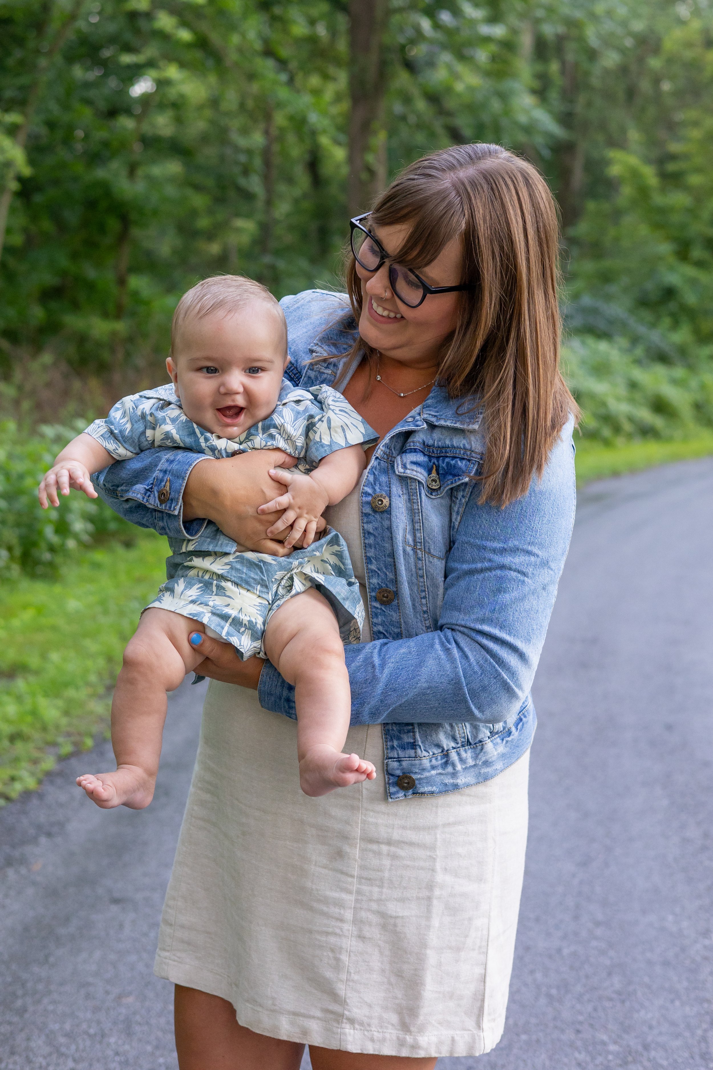 Mom holding baby and smiling laughing with each other candidly at park in Huntington
