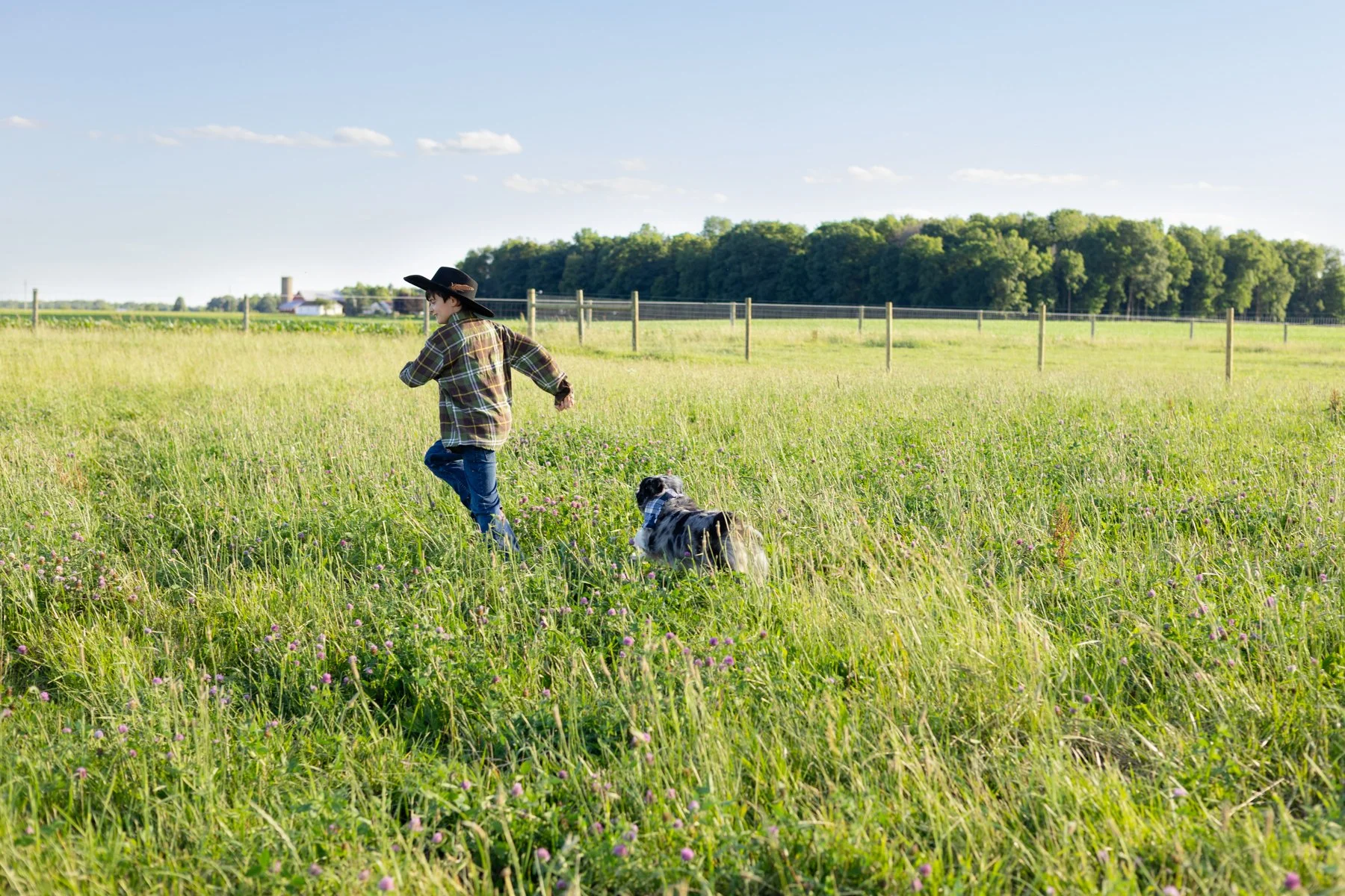 Dog and boy photographed running through tall grasses