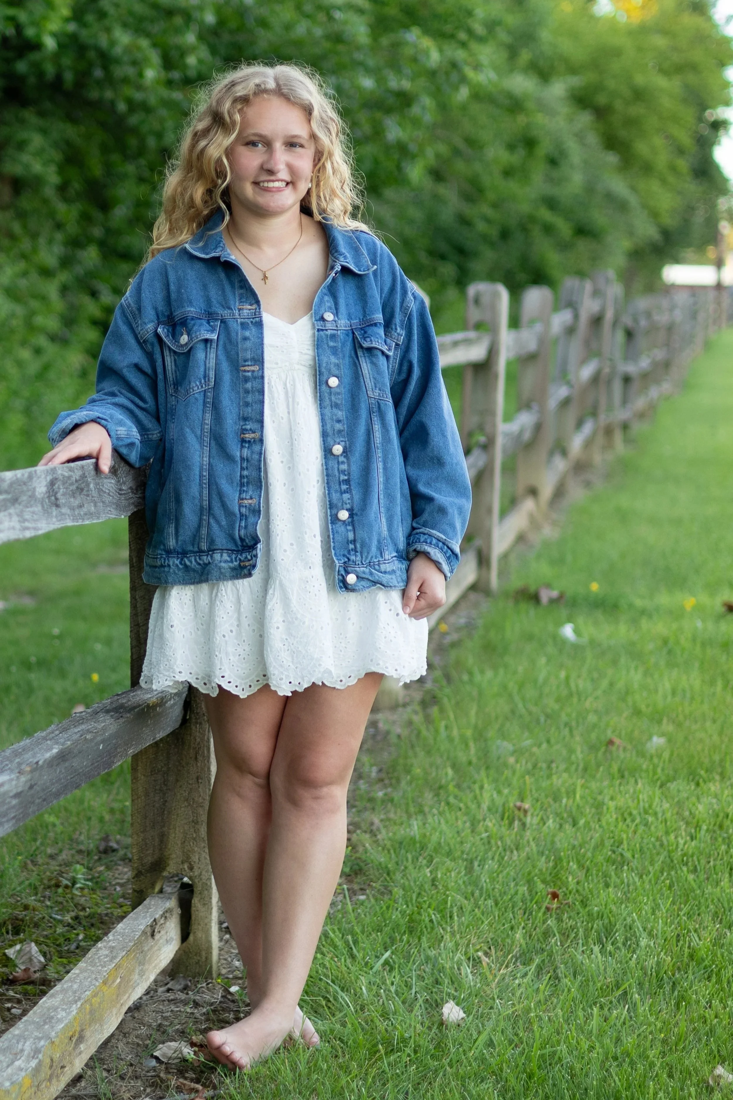 Senior at Homestead High School Fort Wayne Indiana leaning on a fence and photographed using natural light candid pose