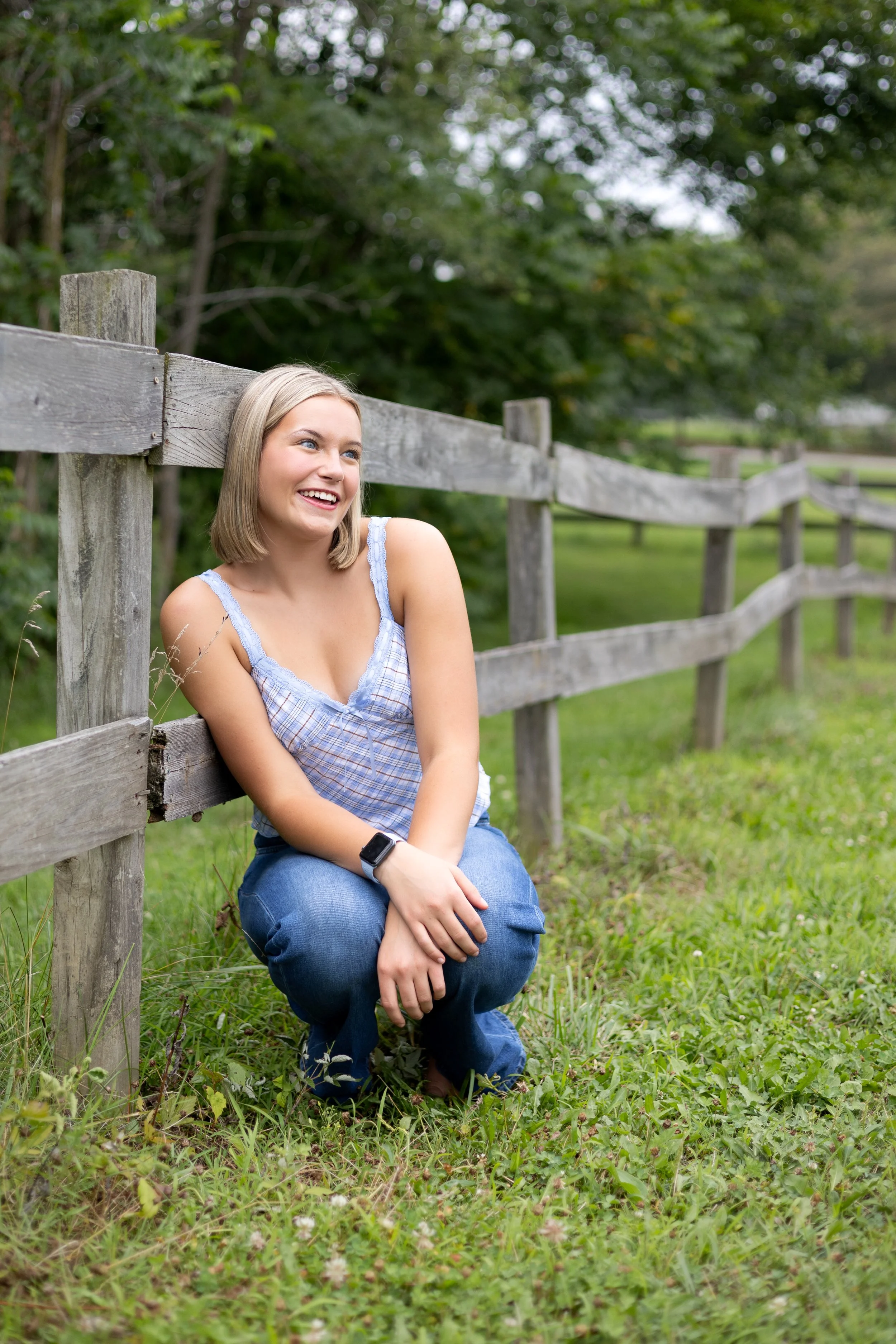 Senior leaning on a fence and looking away with a natural smile taken in Huntington