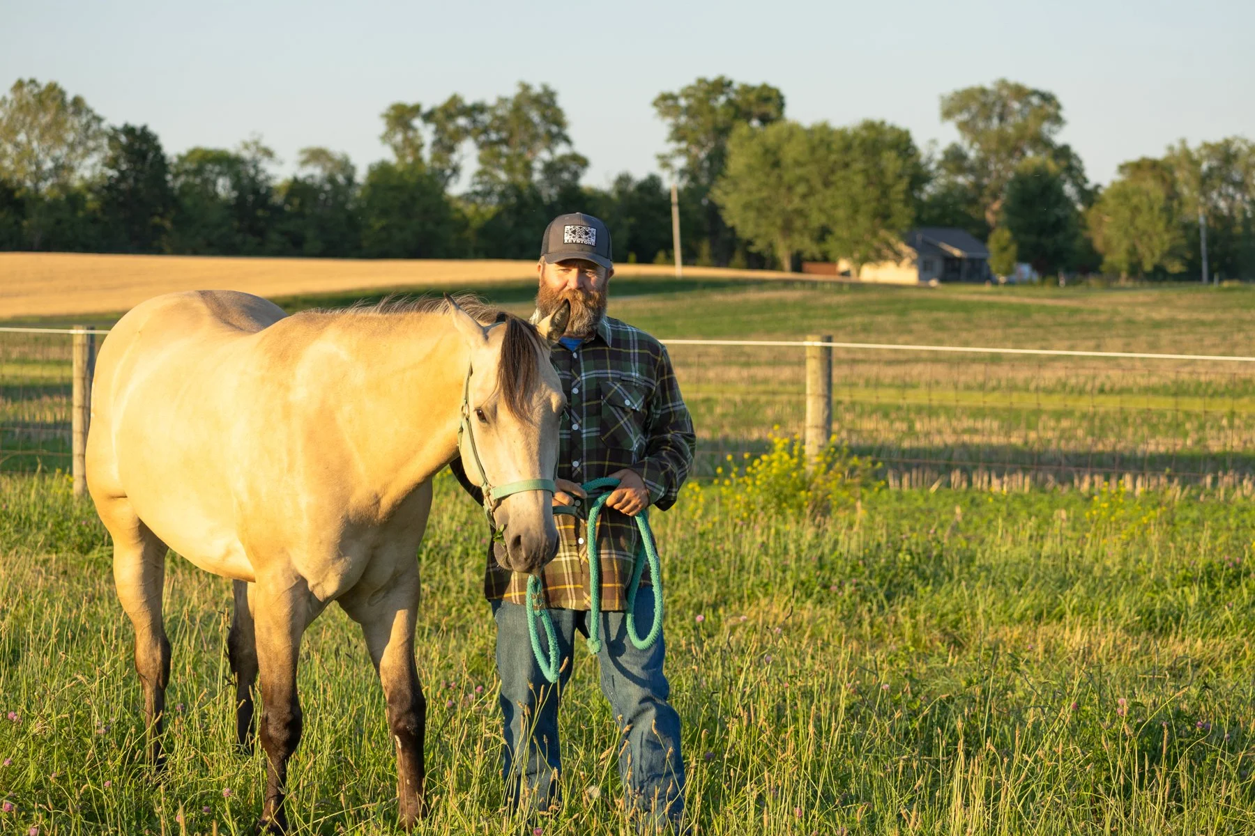 Man and horse in a North Manchester, Indiana pasture at sunset time with trees behind them