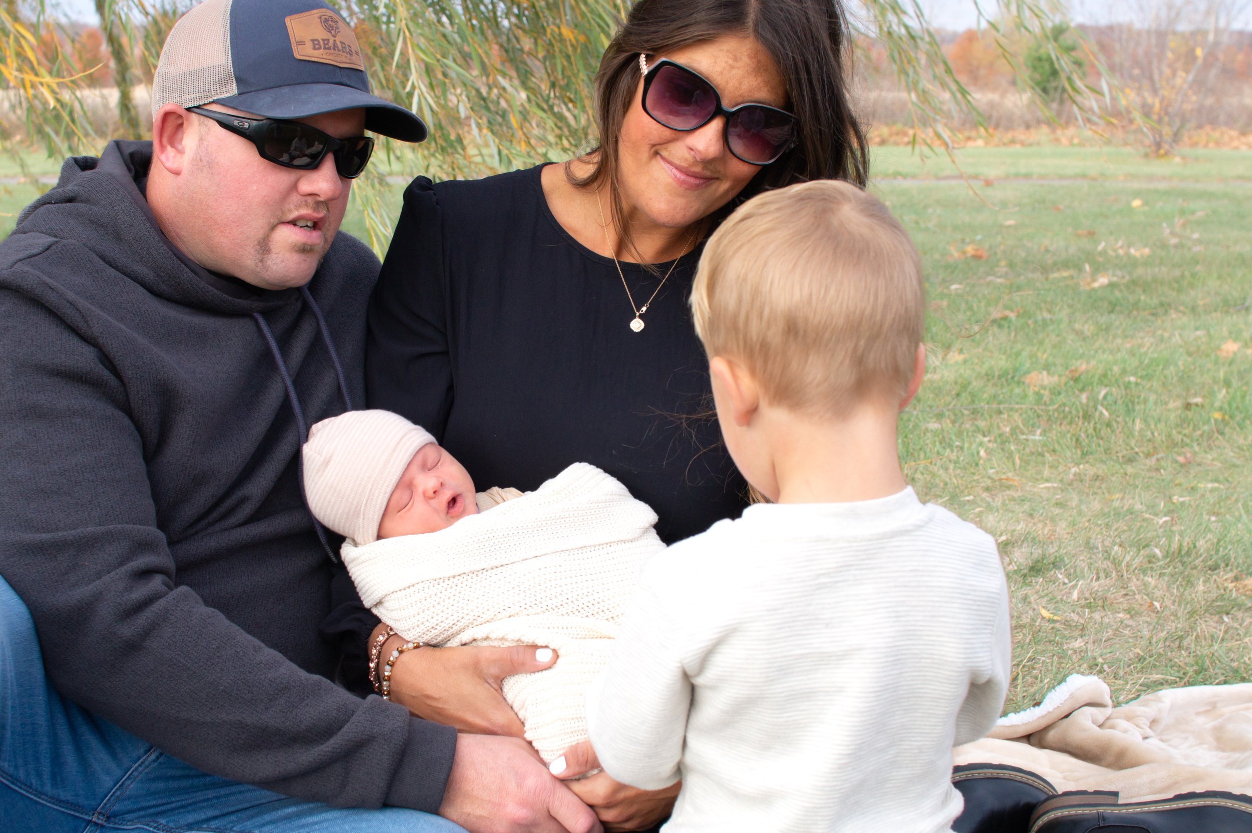 Family welcoming a baby through photographs in Huntington with willow tree behind them