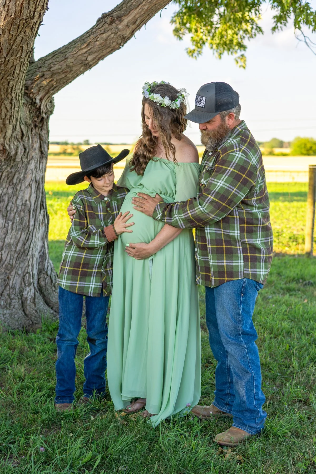 Family excited about a newborn arriving soon all standing under a tree and near a farm in North Manchester, Indiana