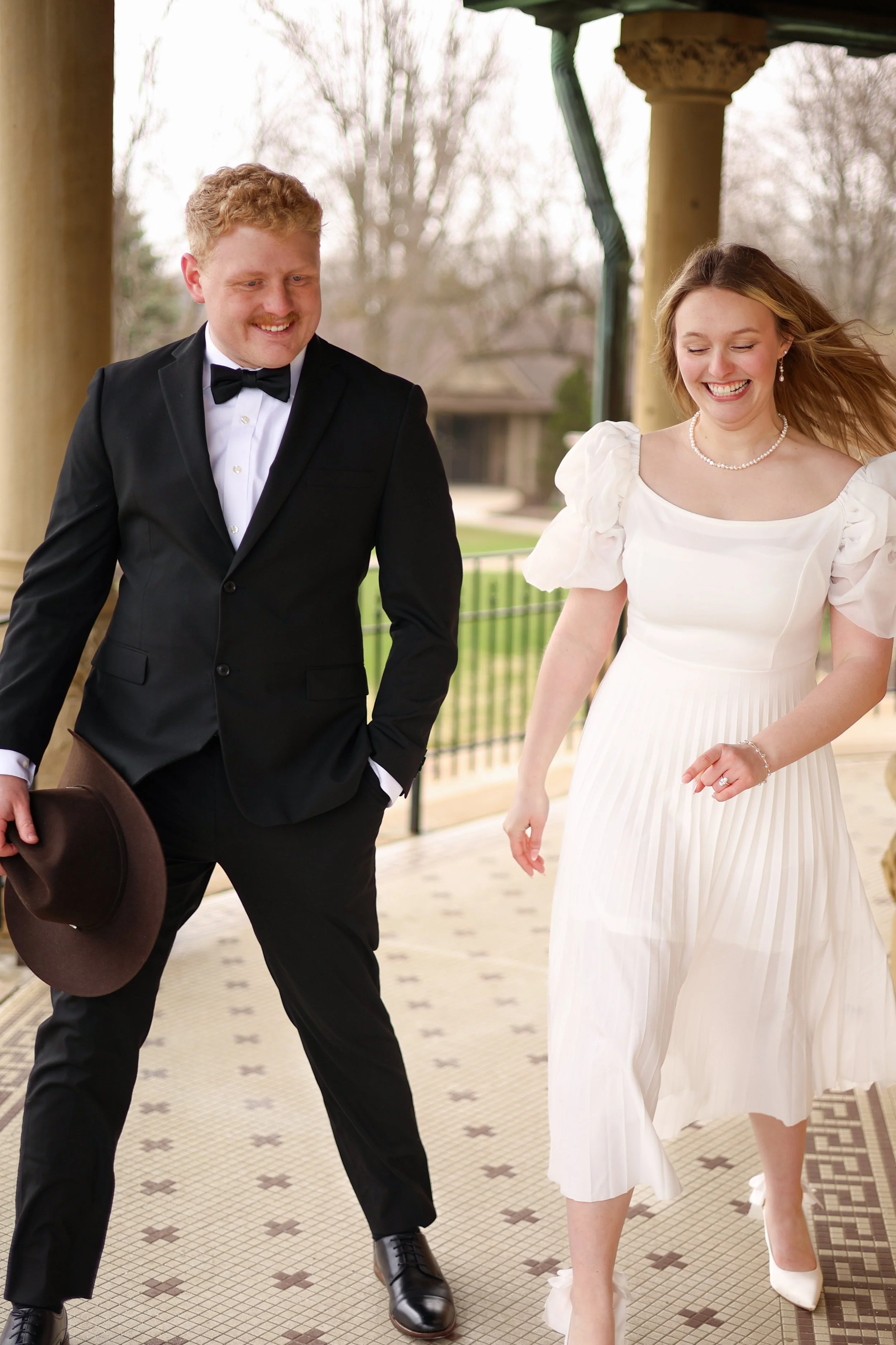 Man and woman walking together and laughing candidly at the moment dressed nicely to announce their upcoming wedding photographed at st francis in fort wayne