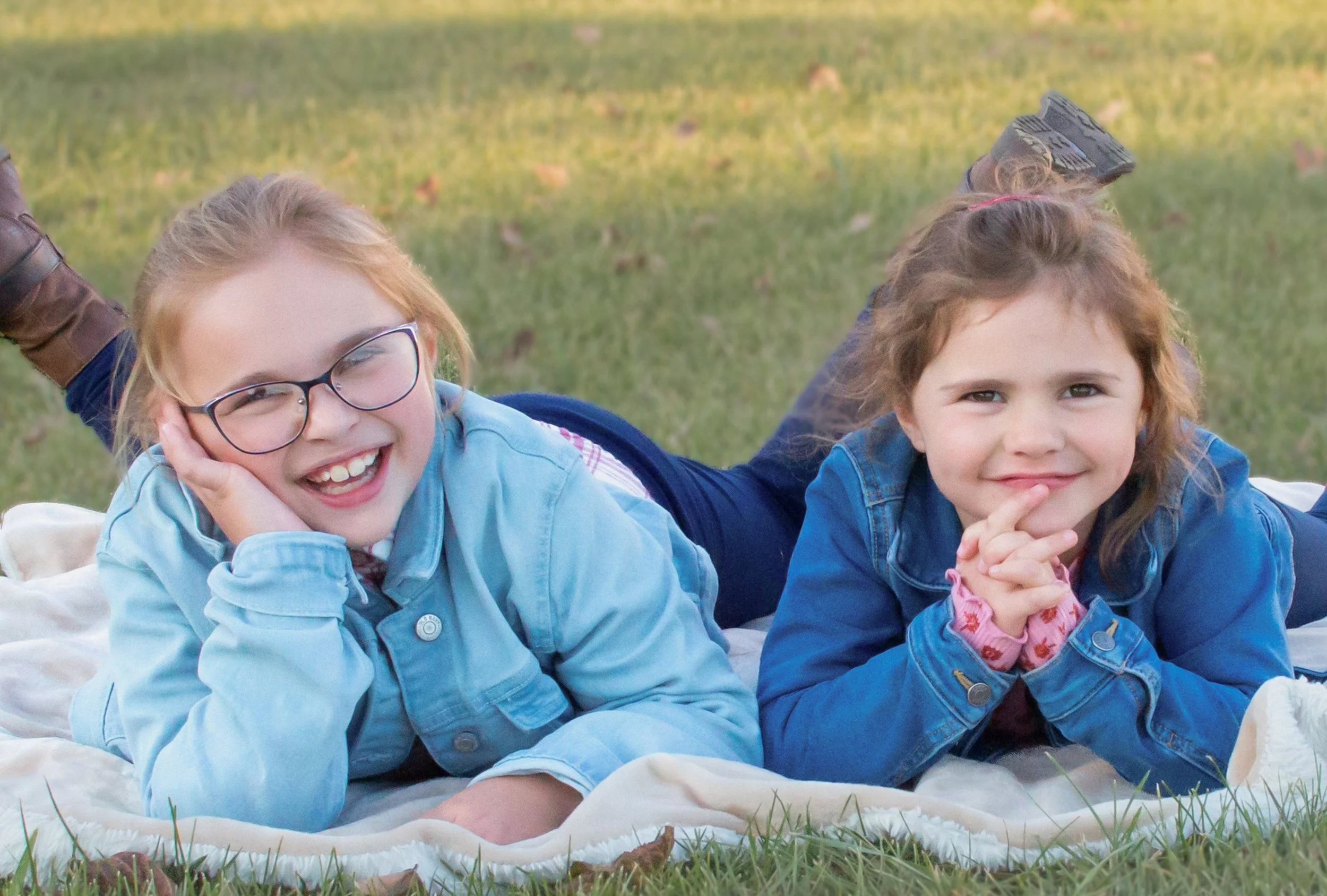 Sisters laying on blanket in grass in Garrett Indiana captured by family photographer
