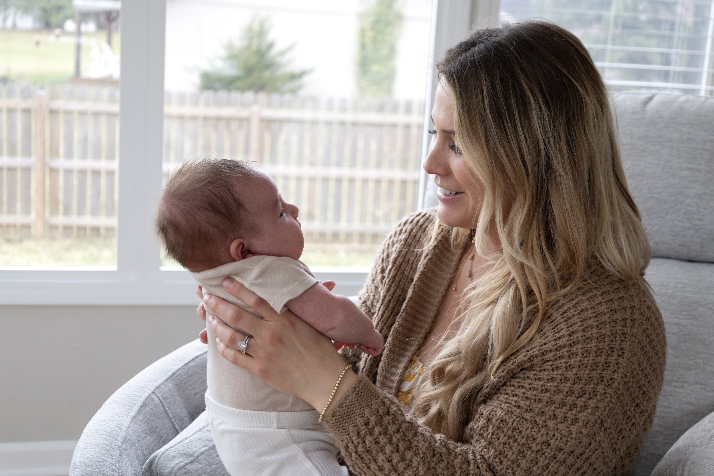 Newborn being held and looked upon lovingly by mom photographed in a home in Huntington