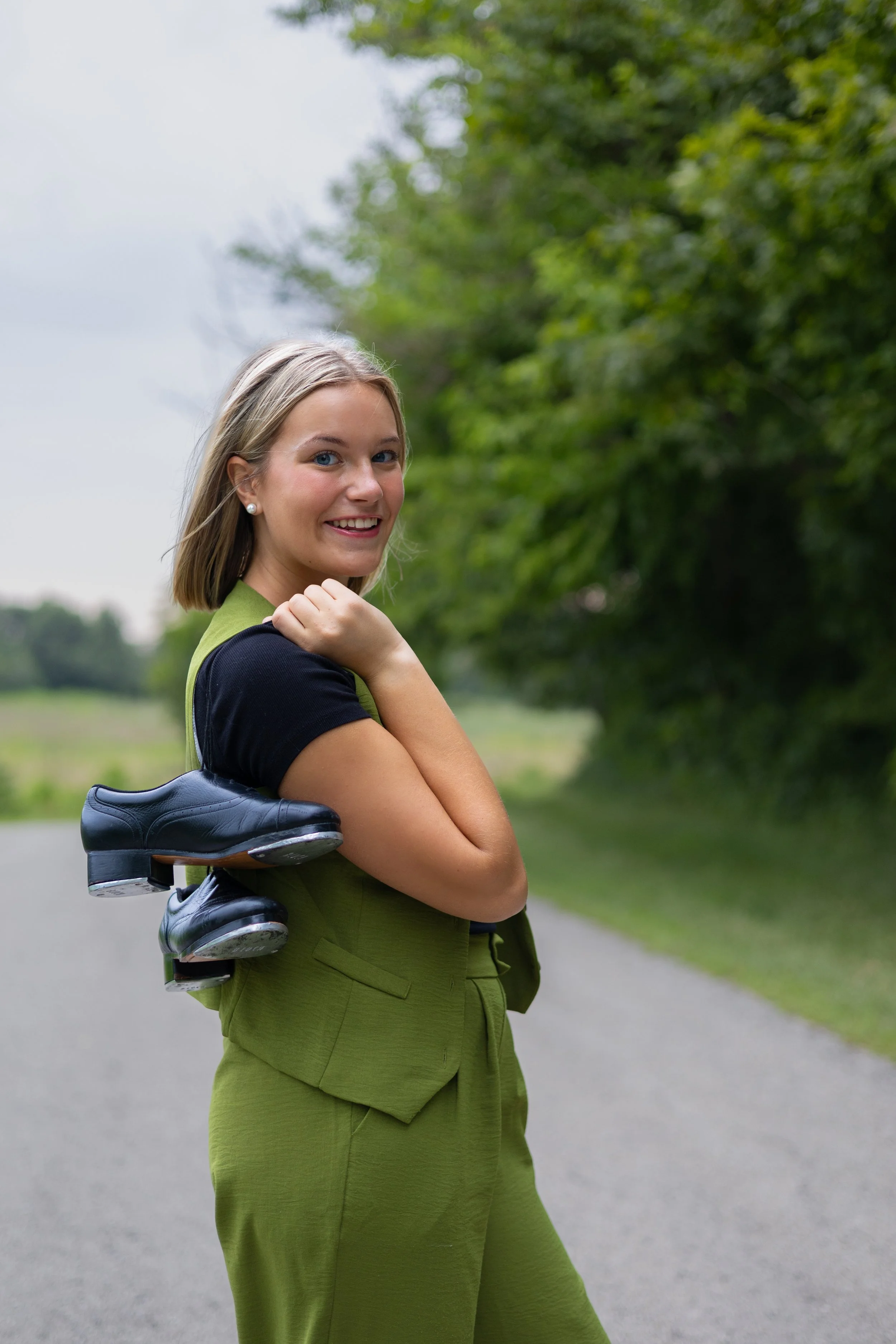 Senior photography of a girl with dance shoes in Huntington with trees behind