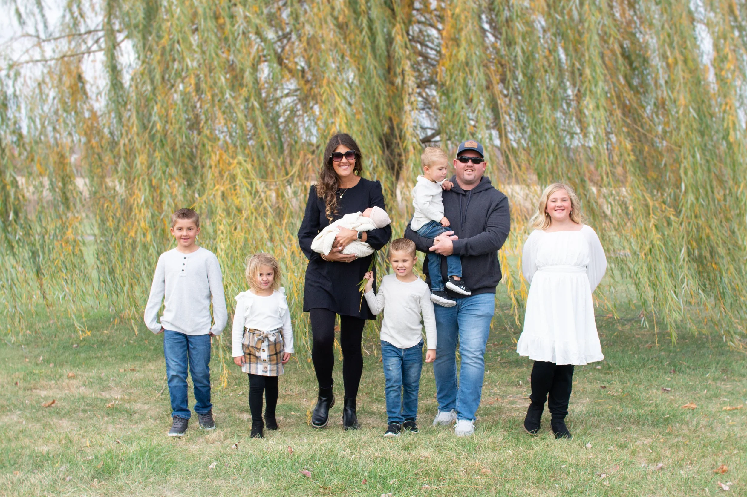 Family photographed with their newborn baby under a willow tree in Huntington Indiana