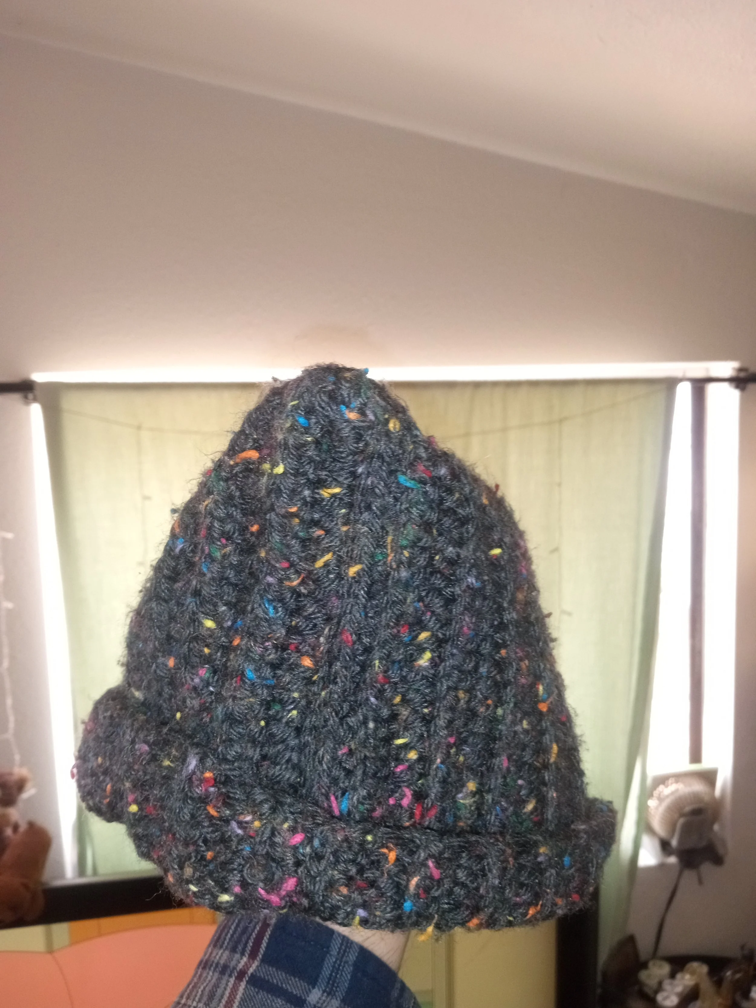 Close-up of a person's head with short, curly black hair with colorful confetti scattered throughout.
Artisan, Handmade, Grass valley, nevada county, Kale Burnett, Crocheted Beanie, art.