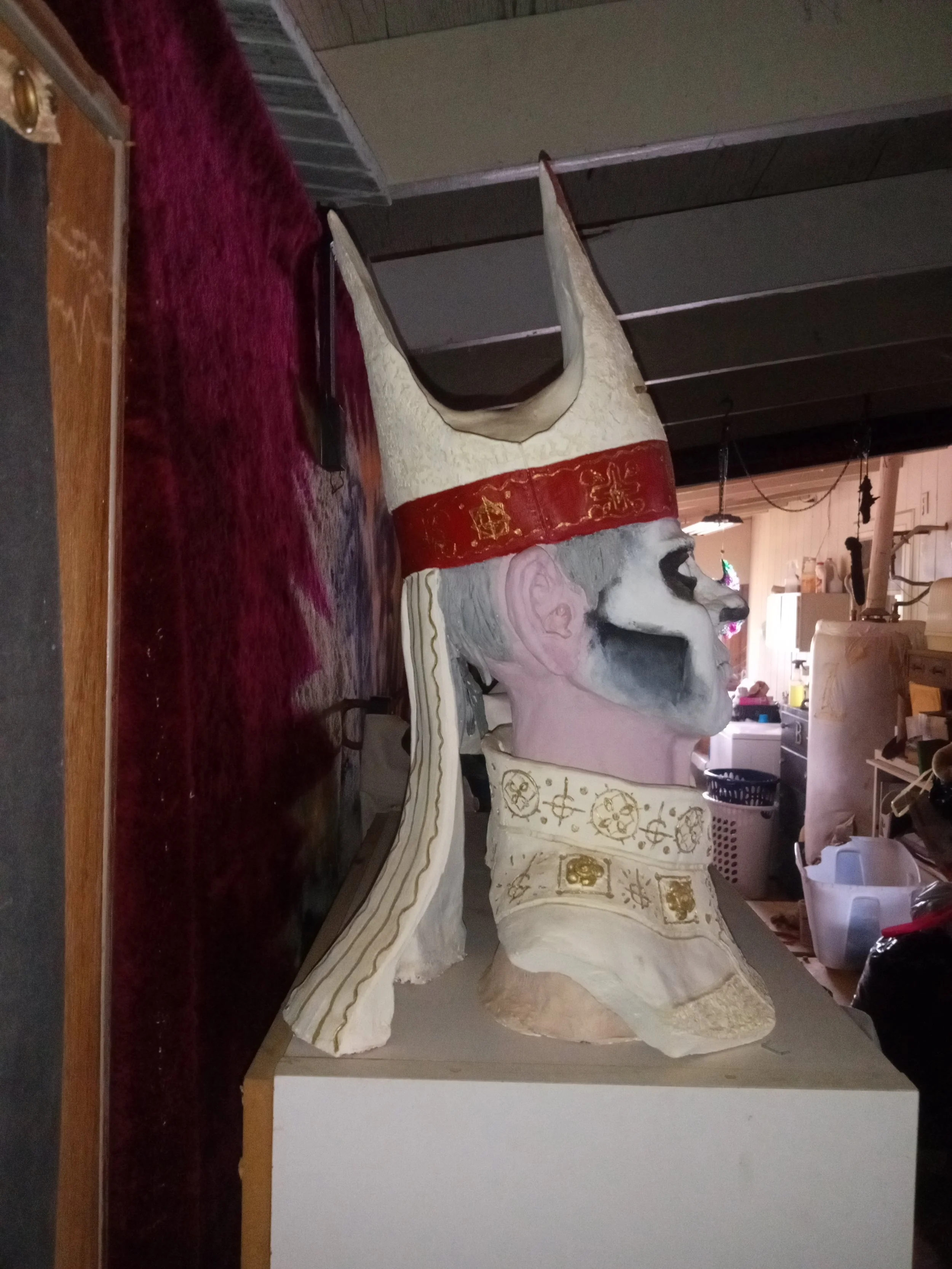 A large, carved bench or sculpture resembling a mythical creature with a horse-like figure and a stylized face, surrounded by a velvet curtain and other furniture in a room. Artisan, Handmade, Grass valley, nevada county, Kale Burnett, Ceramic Sculpt