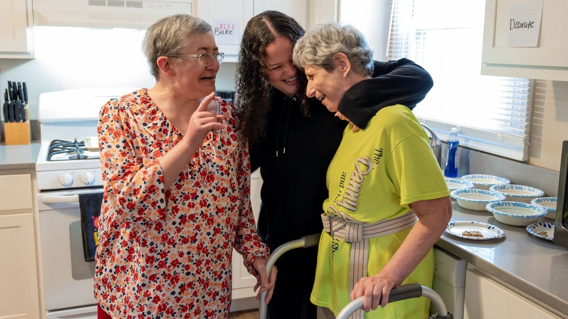 Adults laughing together during an adult services program at the Epilepsy Center of Northwest Ohio, showing supportive relationships, independence, and daily life skills in a home-style setting.