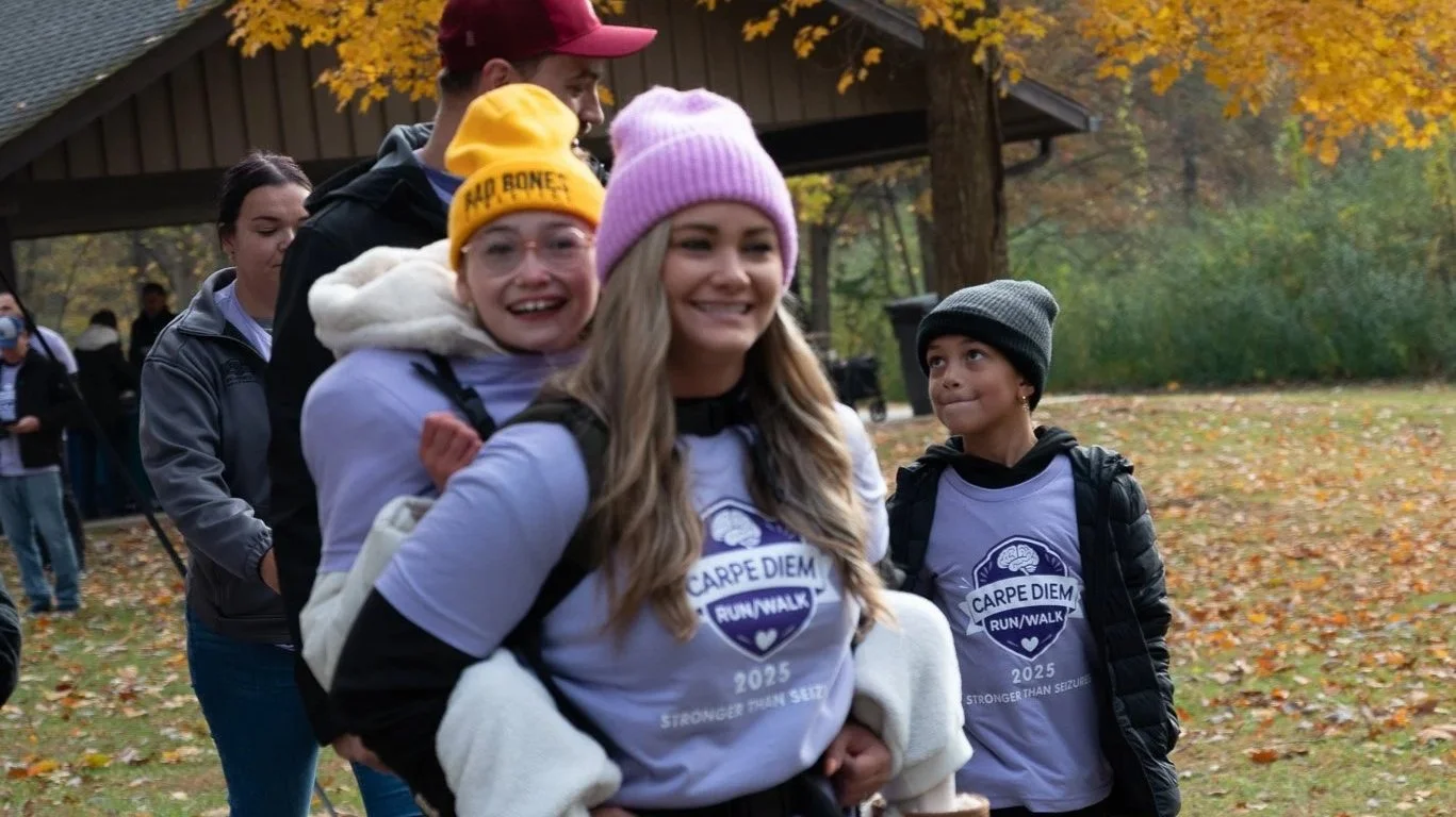 Family participating in the Carpe Diem 5K Run/Walk with the Epilepsy Center of Northwest Ohio, wearing event shirts and smiling together in support of epilepsy awareness and community.