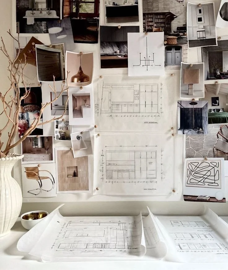 Processus de conceptualisation d'un design d'espace affiché sur un mur, comprenant des plans, des photos de pièces, et des échantillons de matériaux. Un vase blanc crème est à gauche avec des branches sèches de fleurs.