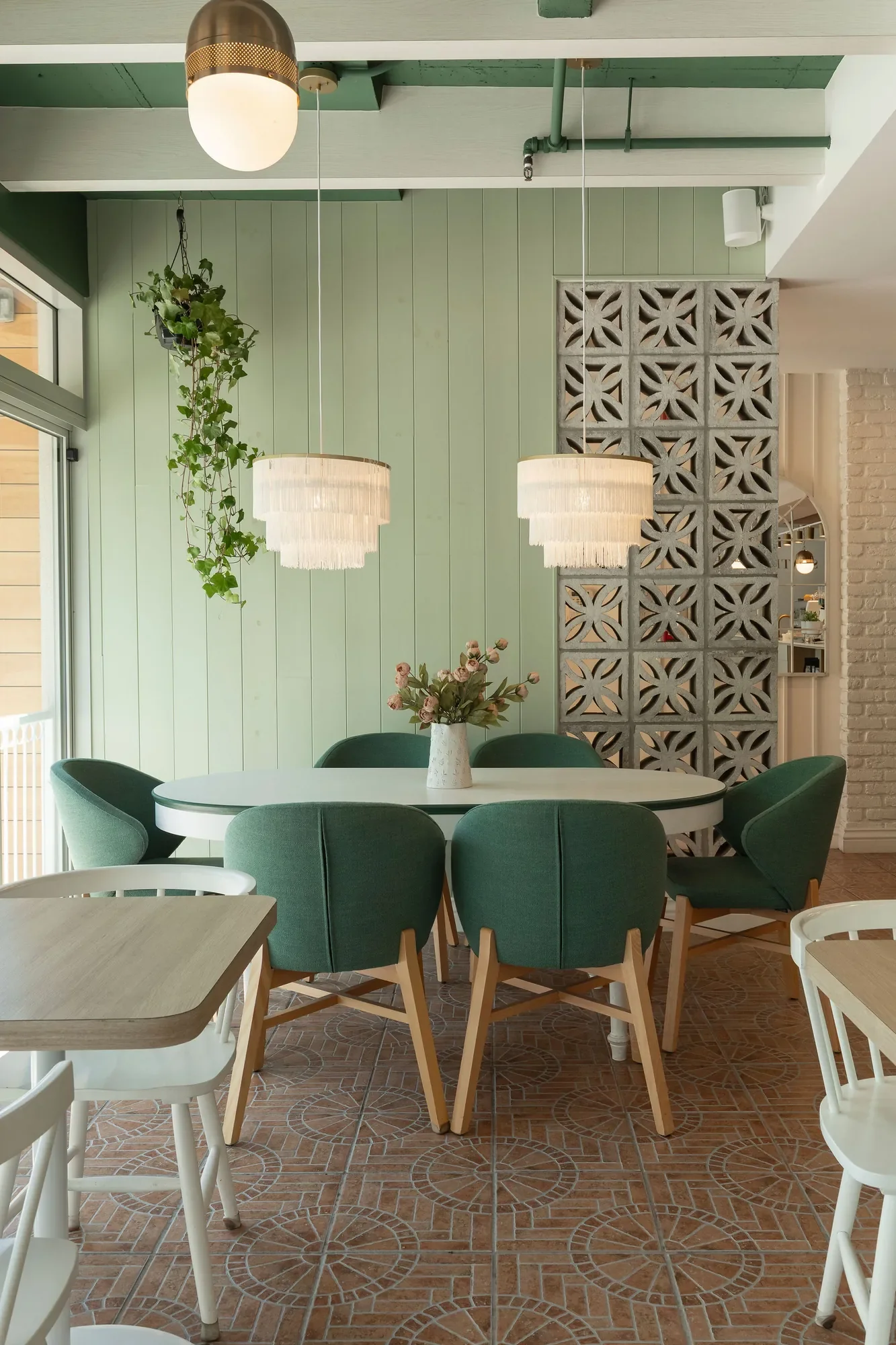 Design d’intérieur de restaurant par Rübik Design : salle verte, claustra en béton et lustres à franges