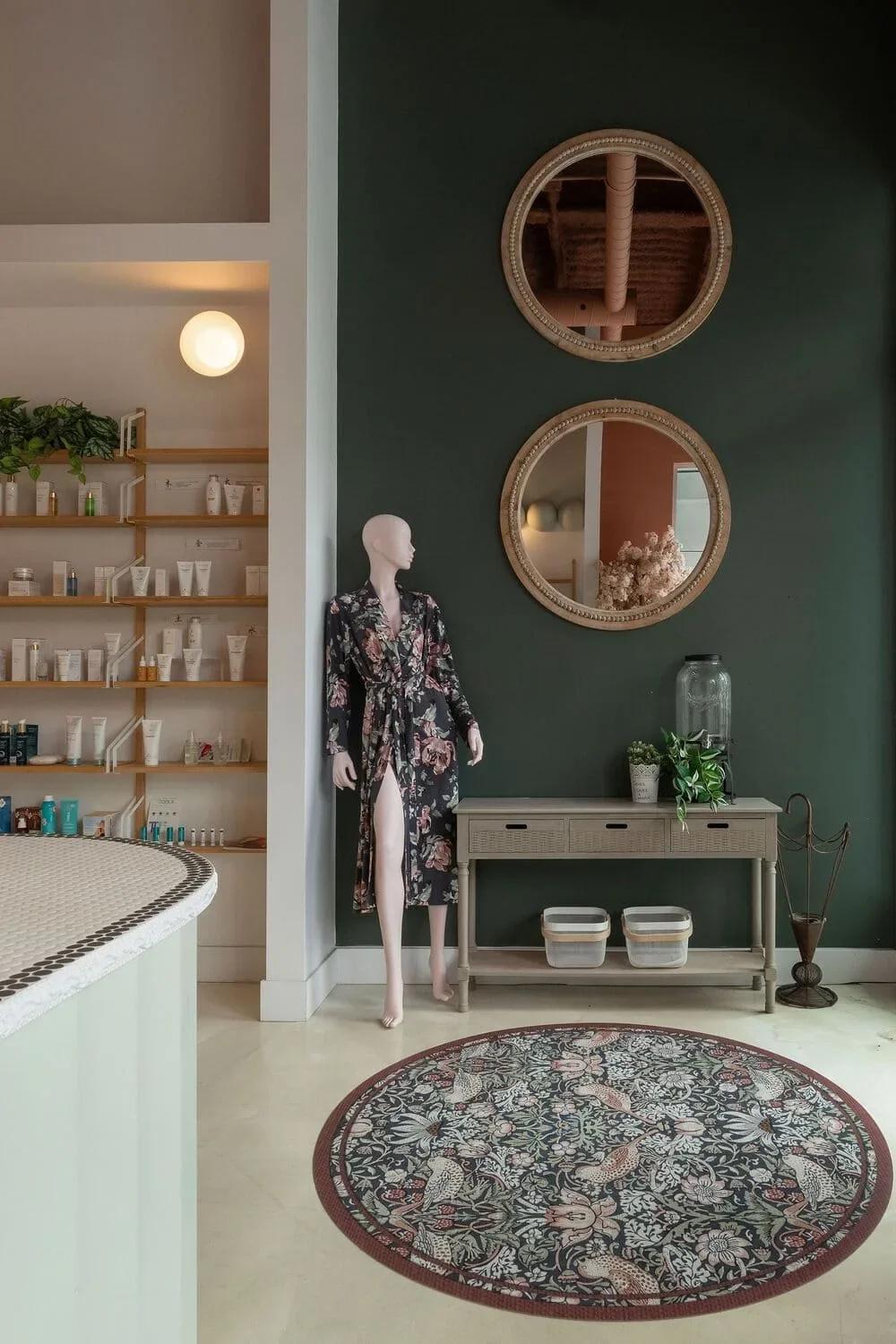 Design commercial à Montréal par Rübik Design : mur vert forêt, miroirs ronds en bois, console et tapis floral