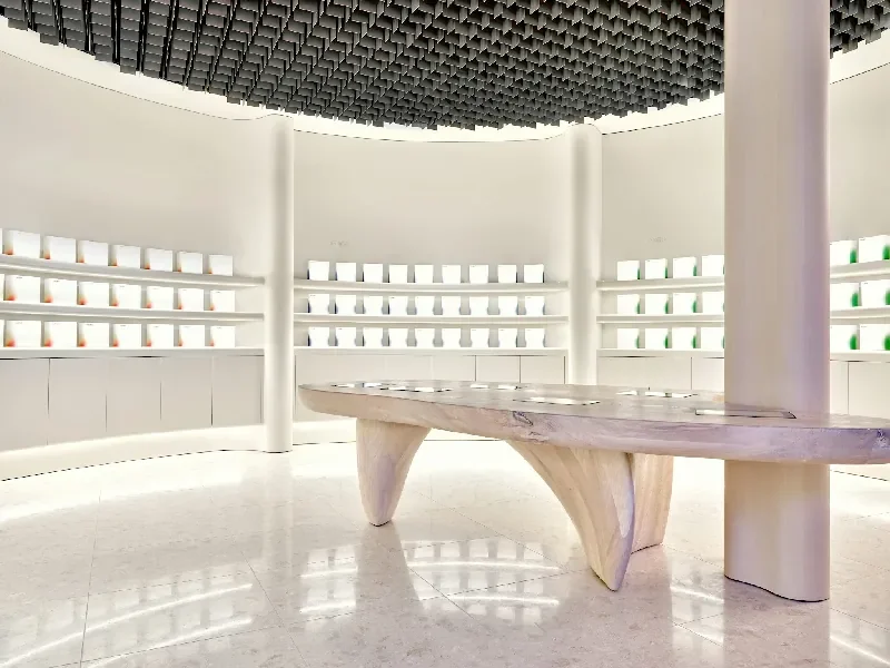 Produits de soin de la peau sur des étagères et tables blanches arrondies dans une boutique moderne