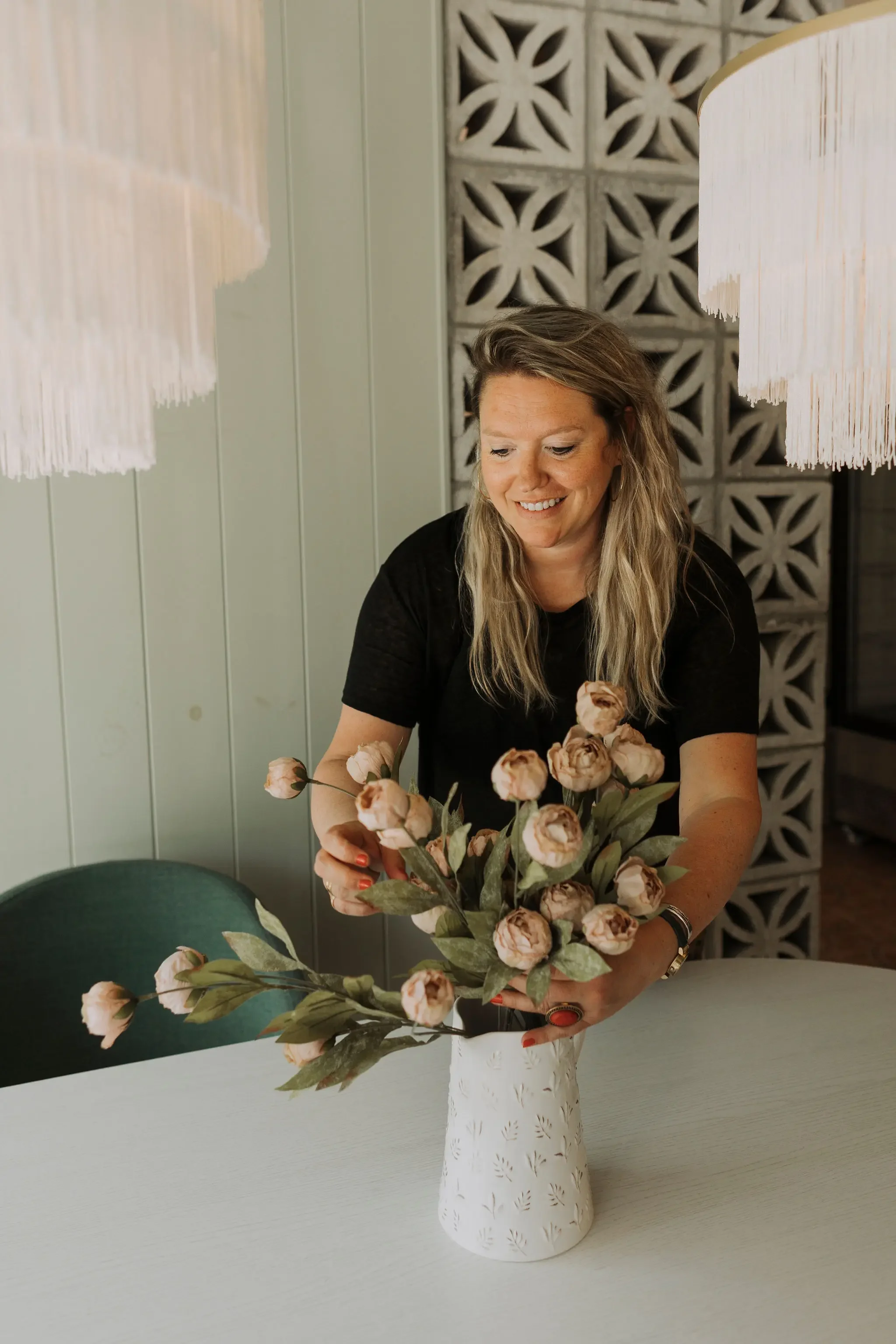 Comptoir de bar en bois d'un projet commercial avec tabourets noirs, luminaires suspendus et étagères à bouteilles