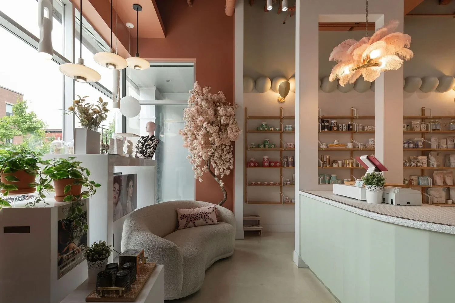 Aménagement d’une boutique à Montréal par Rübik Design : canapé courbe bouclé, cerisier en fleurs, mur terracotta et étagères en bois