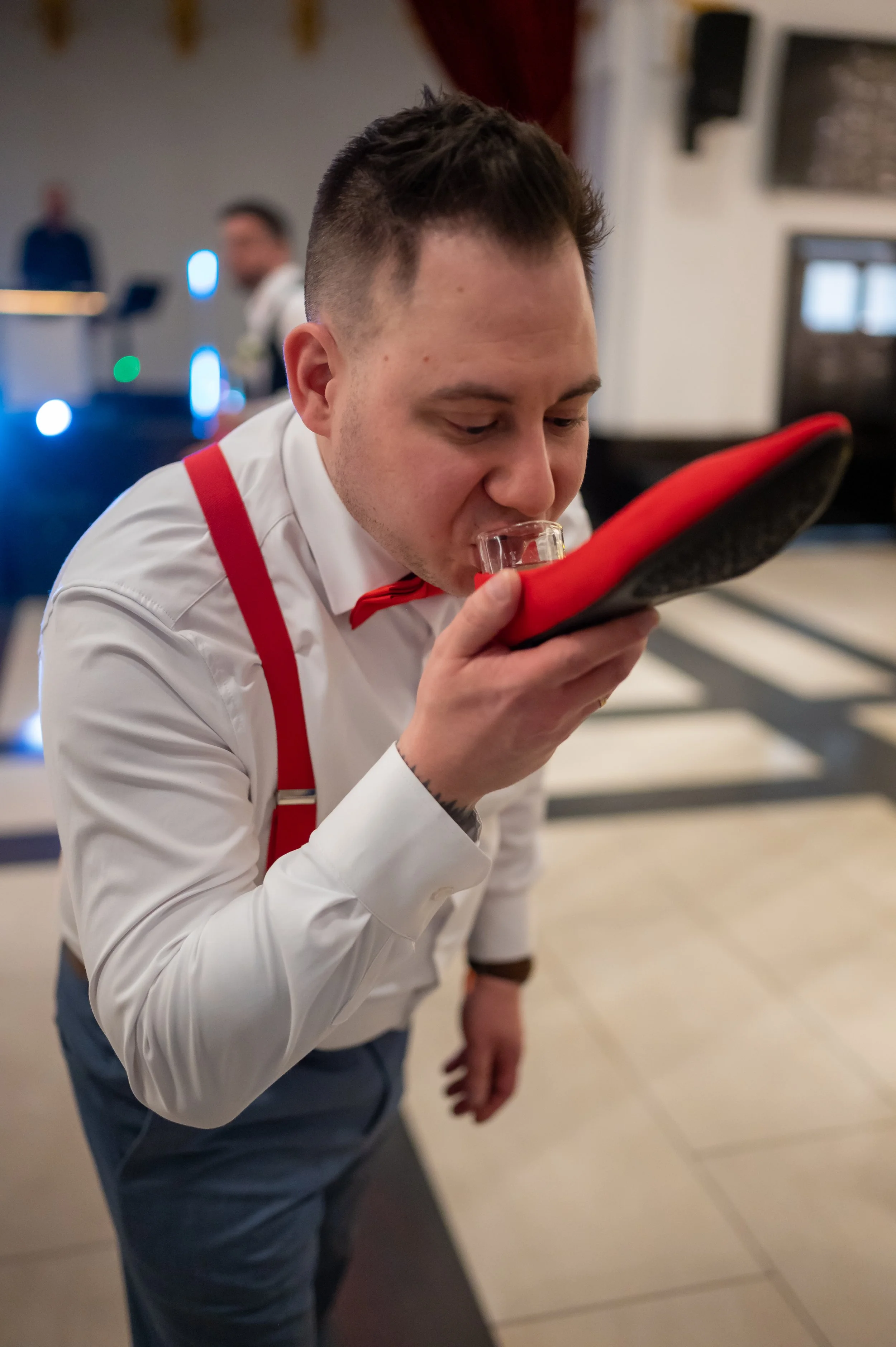 Groom adjusting his watch while getting ready in a room with wooden furniture and floral decorations.