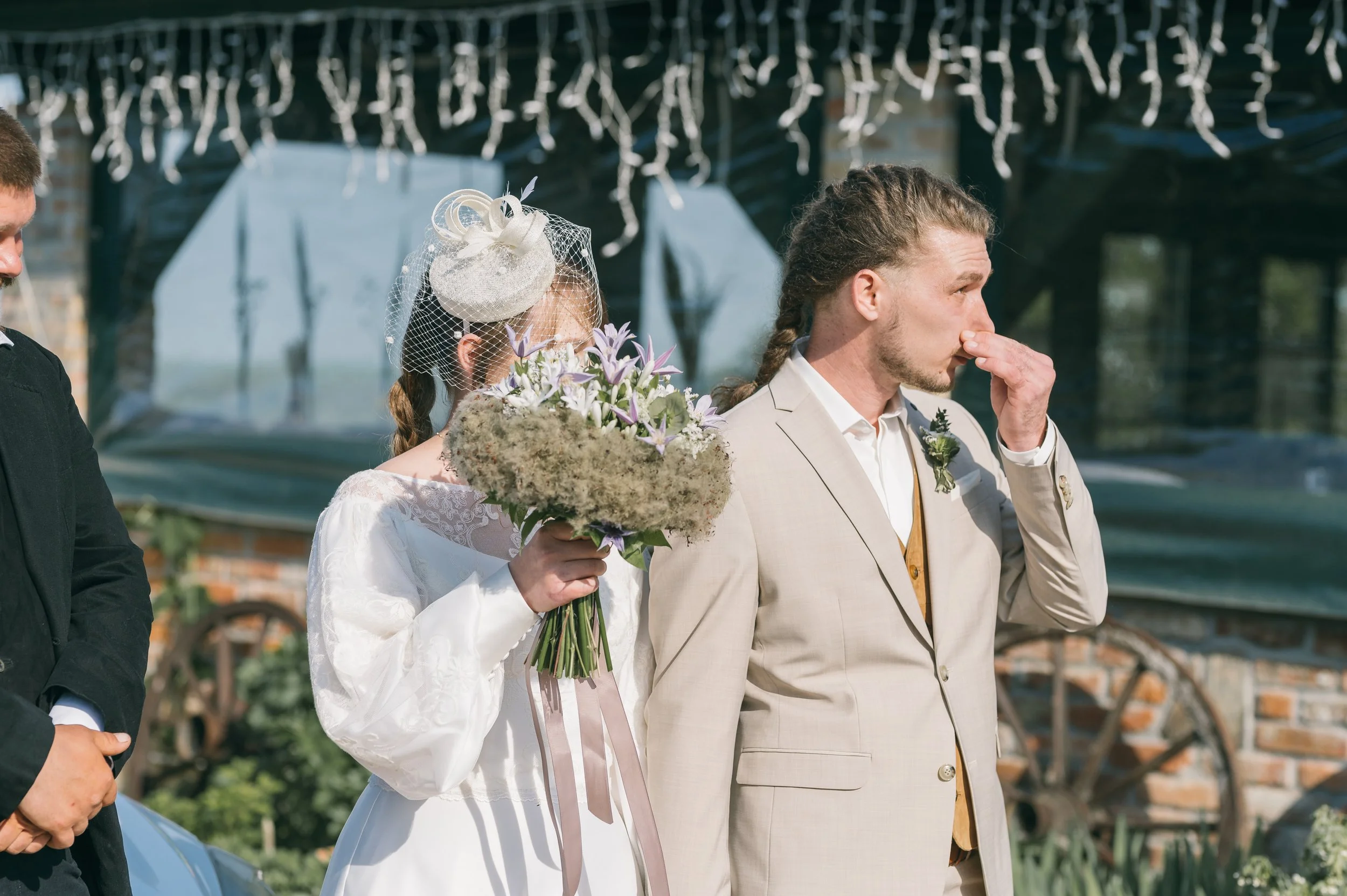 Person adjusting the coat of another person dressed in a beige vest and white shirt, with a focus on their hands and clothing.