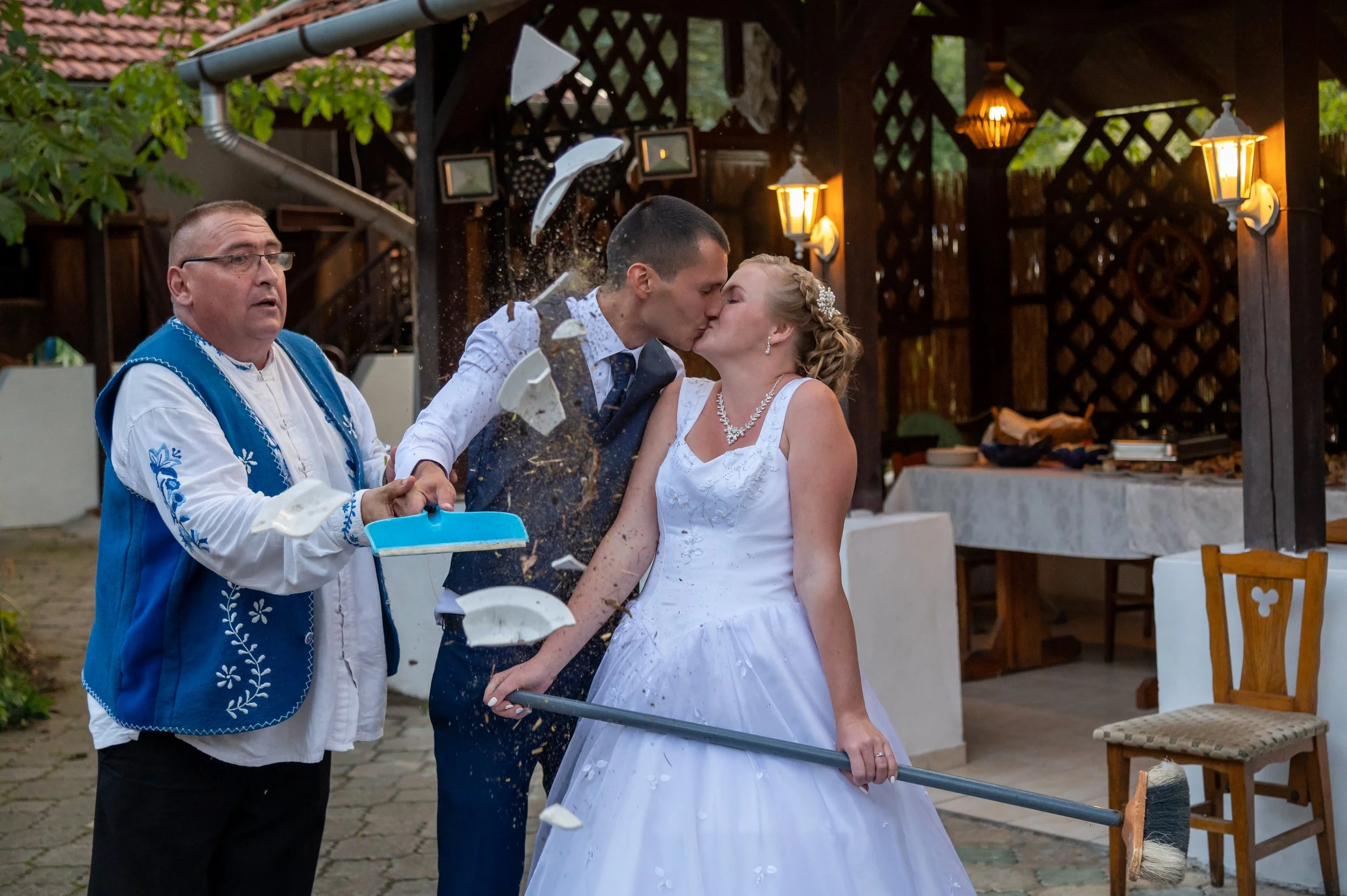 A bride dressed in a wedding gown smiling and interacting with a small dog wearing a dress with a pink bow.