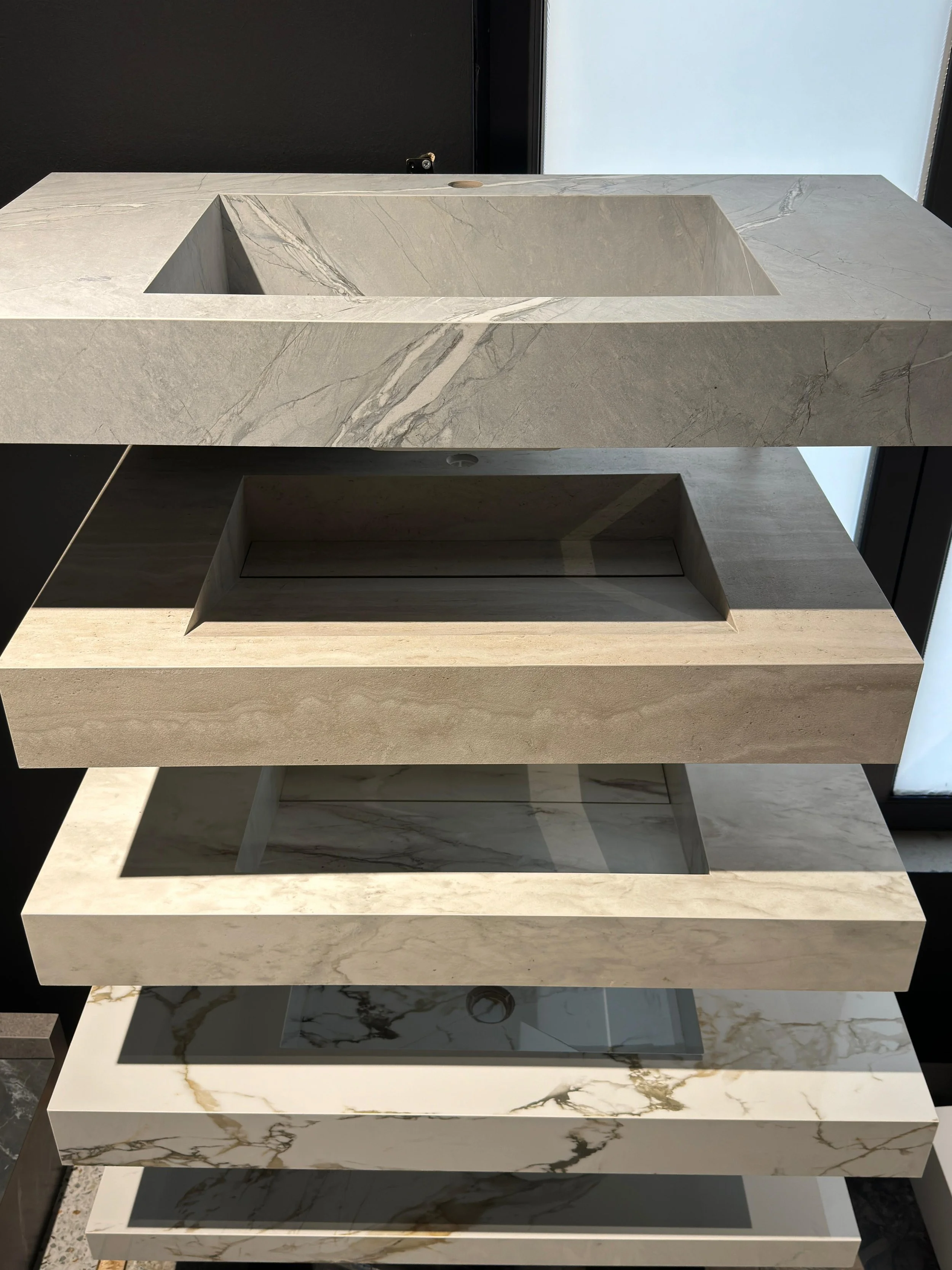 Stacked marble countertop samples in various colors and patterns.