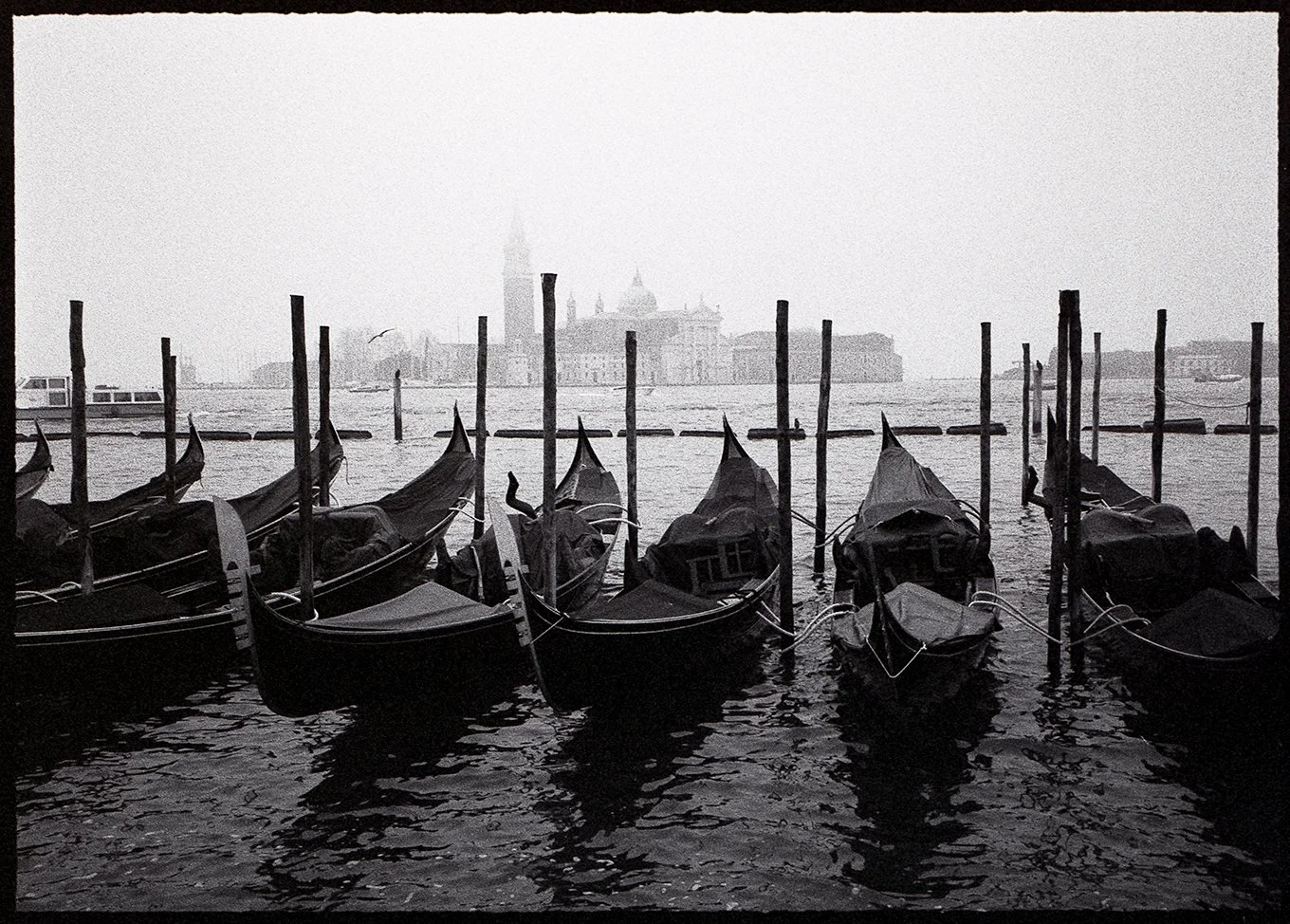 Gondolas docked on the water in Venice black and white on 35mm film Pentax 17