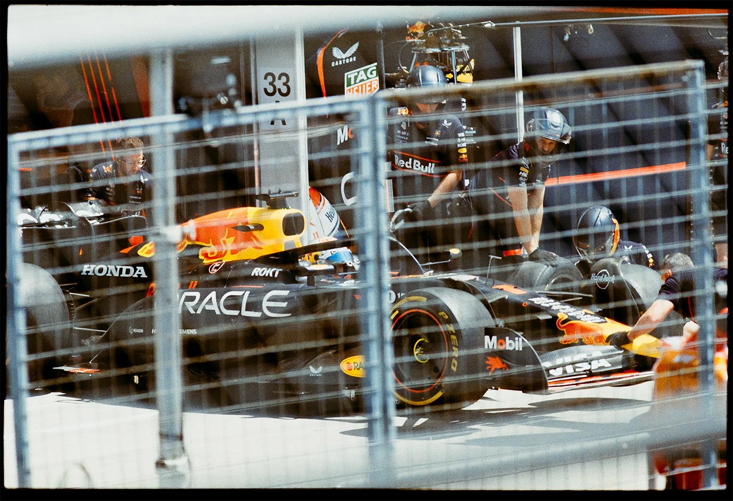 A Red Bull Racing Formula 1 car in the garage with team members attending on 35mm film