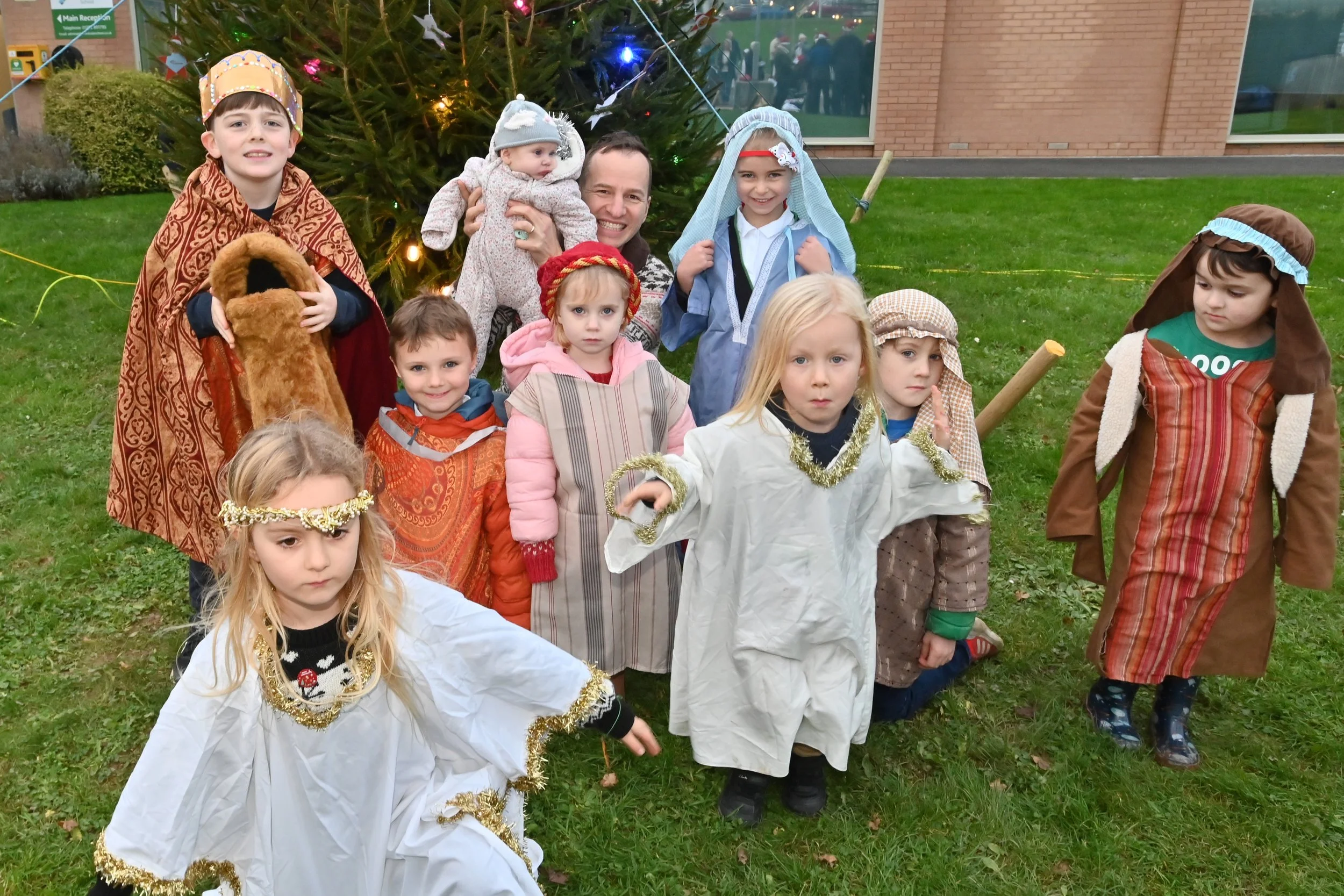 A minister stood with a group of children dressed up as nativity characters, as Christmas time.