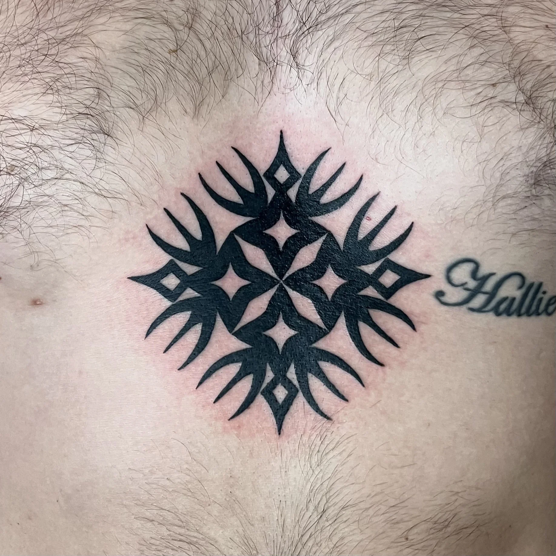 A black geometric tattoo on a person's chest.